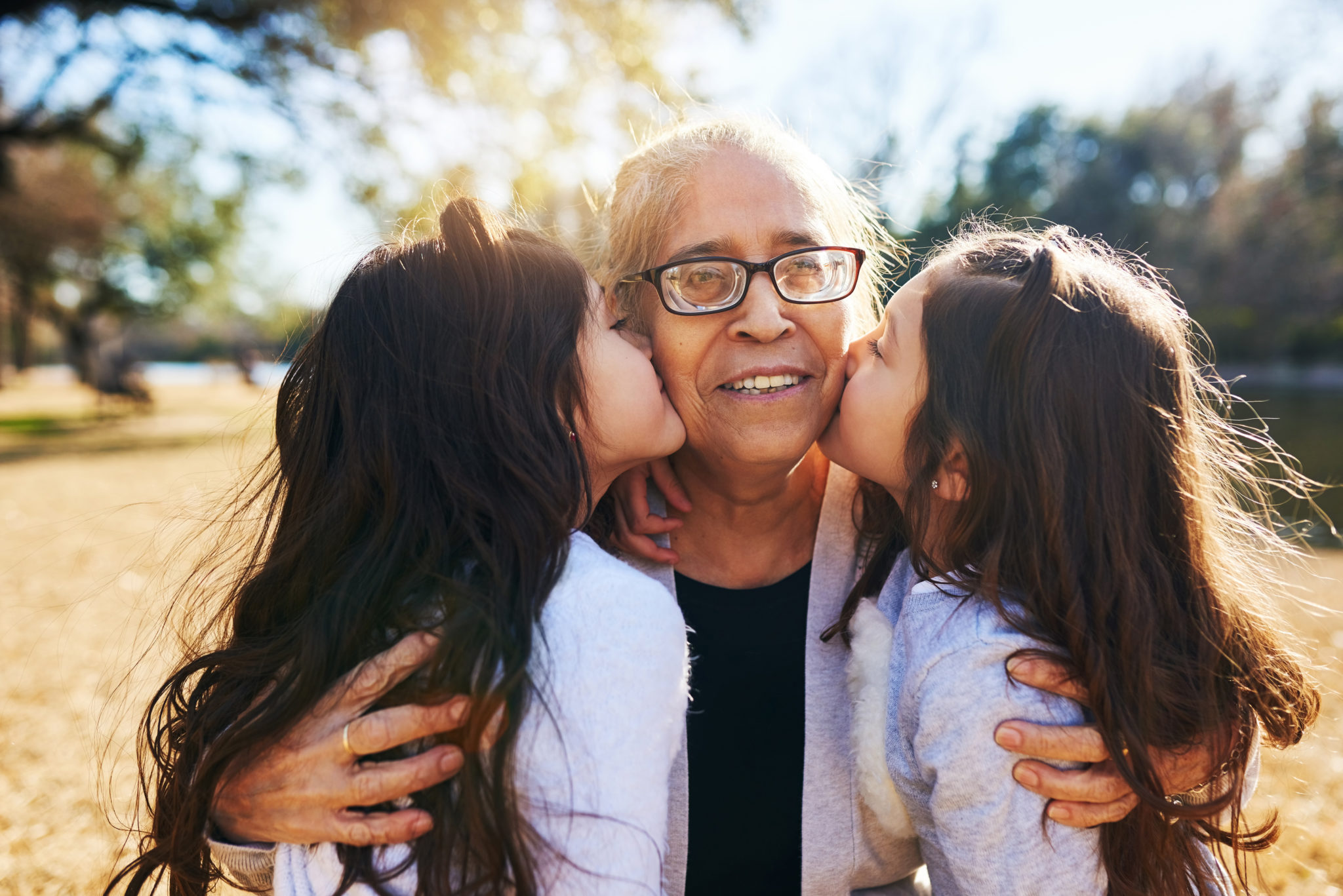 2 girls with long dark hair kiss elderly relative's cheeks