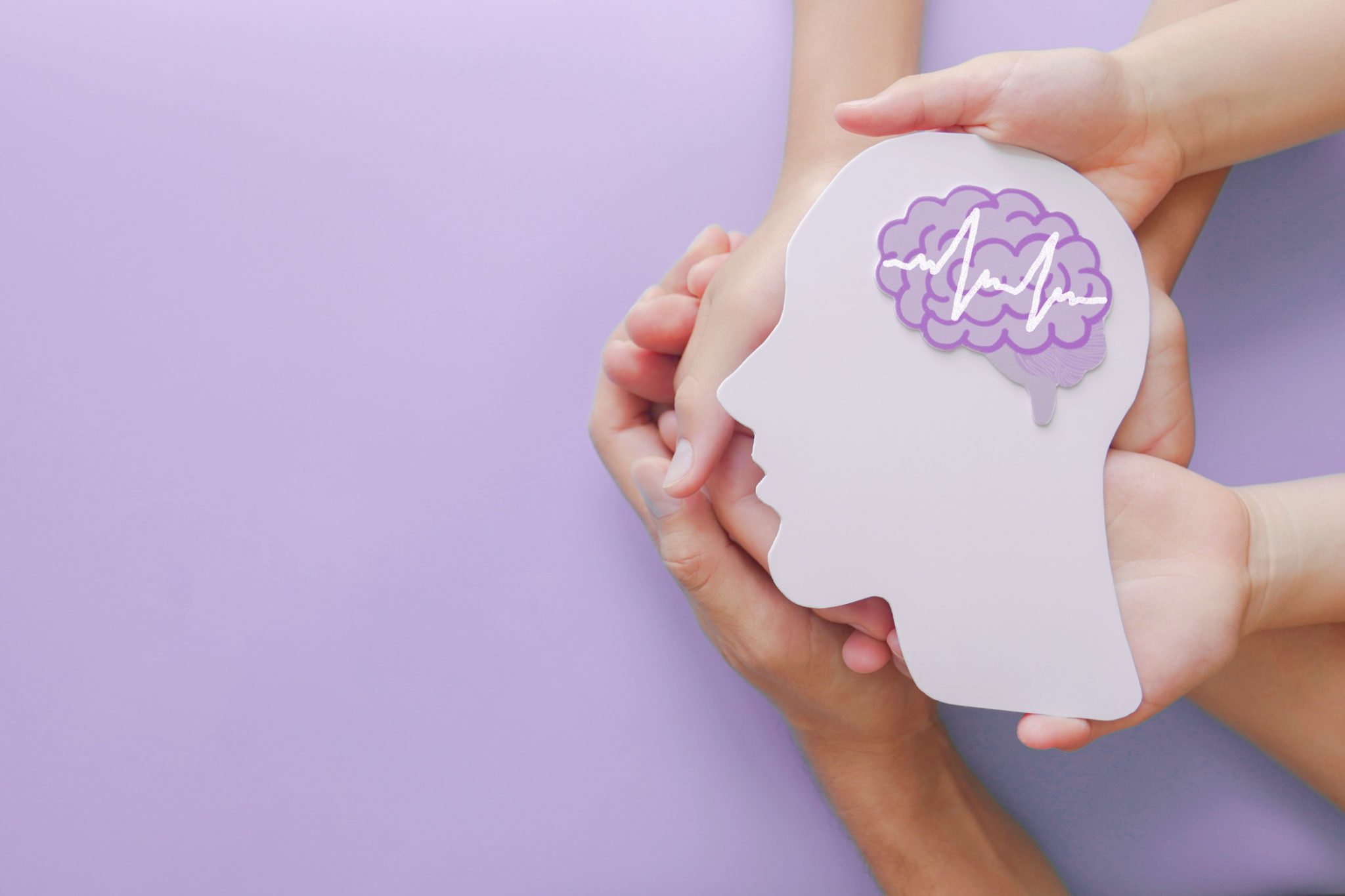 hands hold white cutout head shape with purple brain graphic
