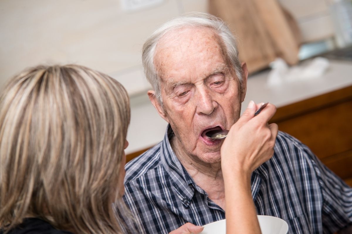 old man opening mouth for spoonful of foodto eat spoonful of food