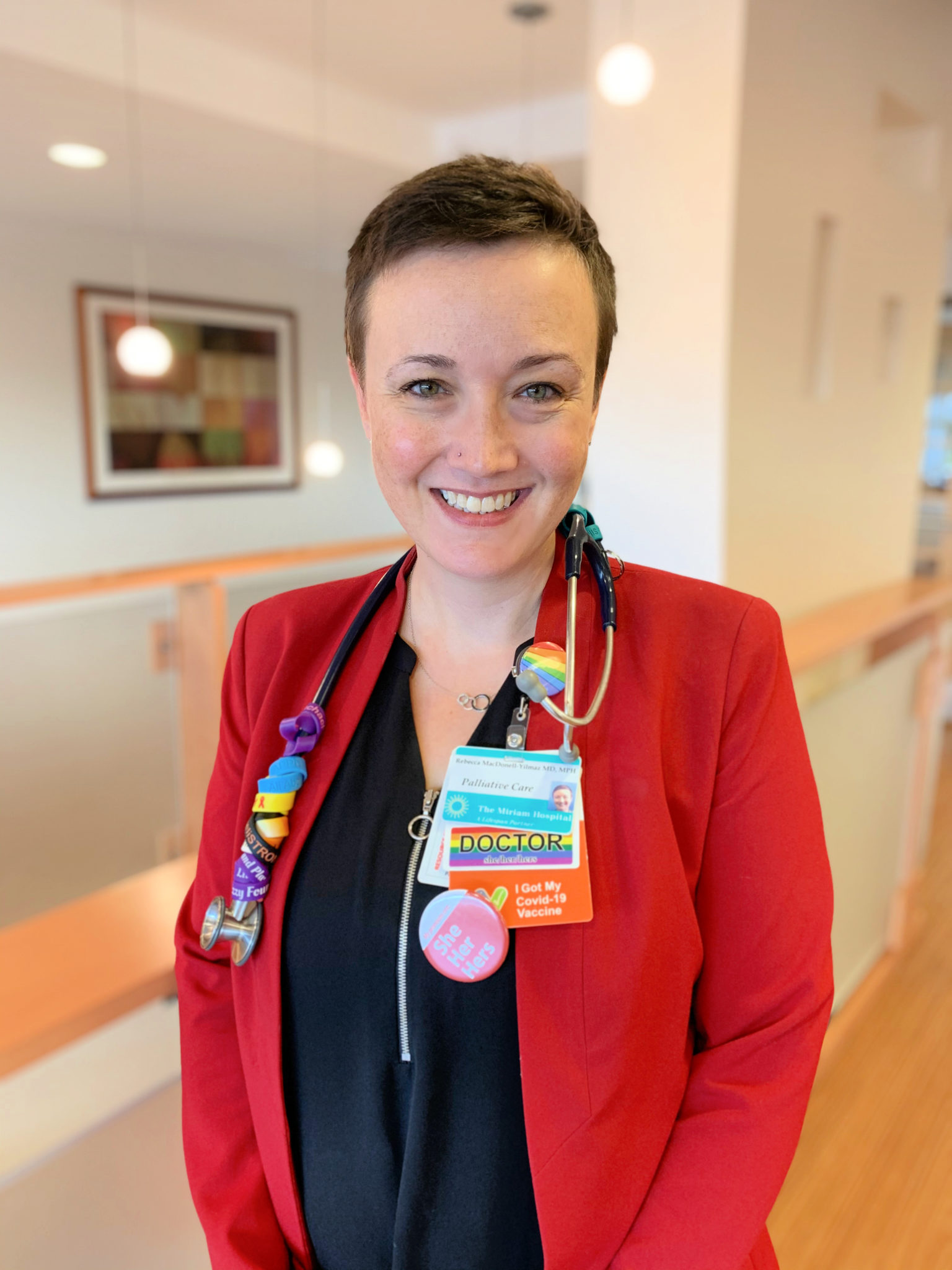 Pediatric hospice doctor wearing bright red jacket and stethoscope smiles in the Hulitar Hospice Center