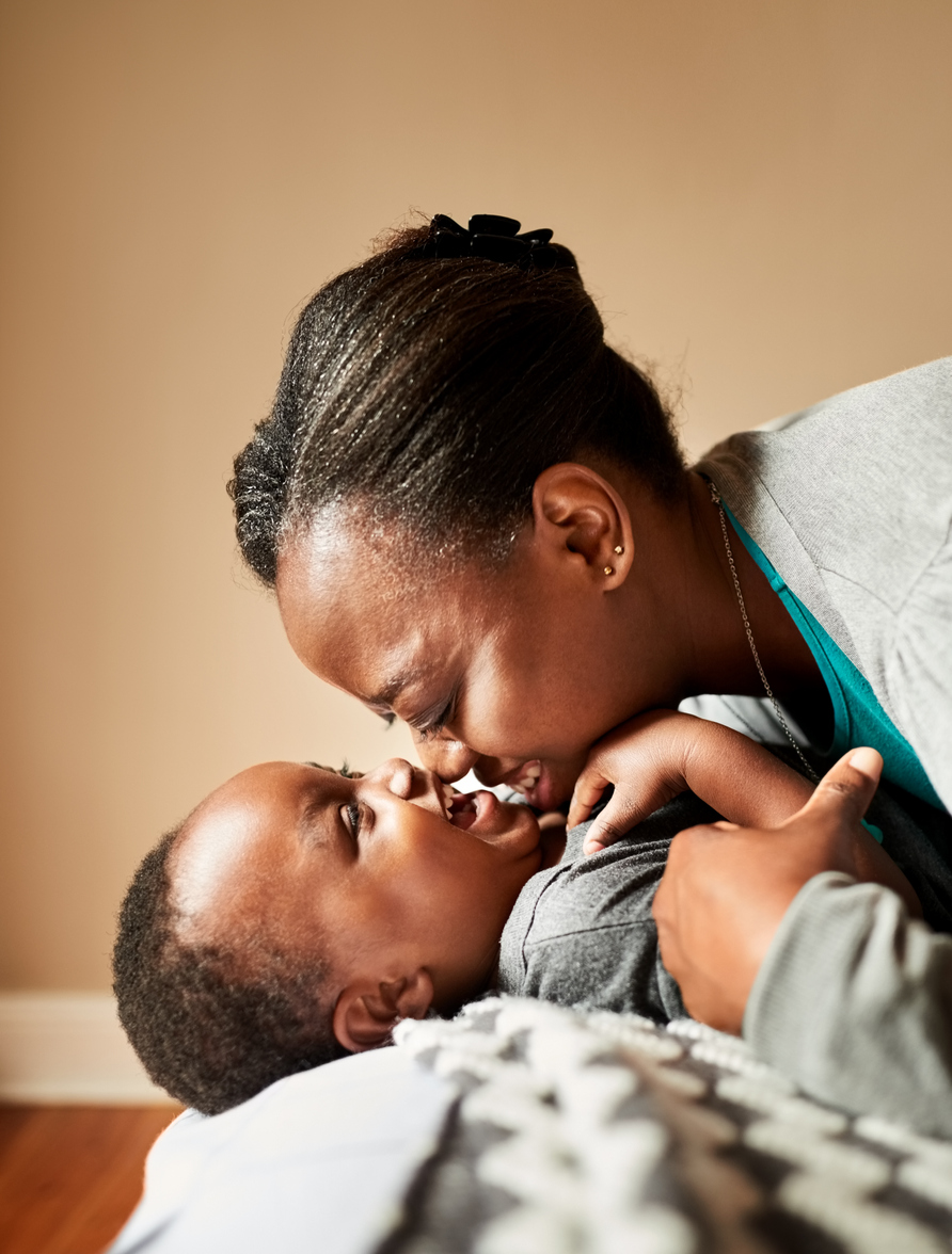 Close-up of a young mother playing with her cute daughter on bed at home