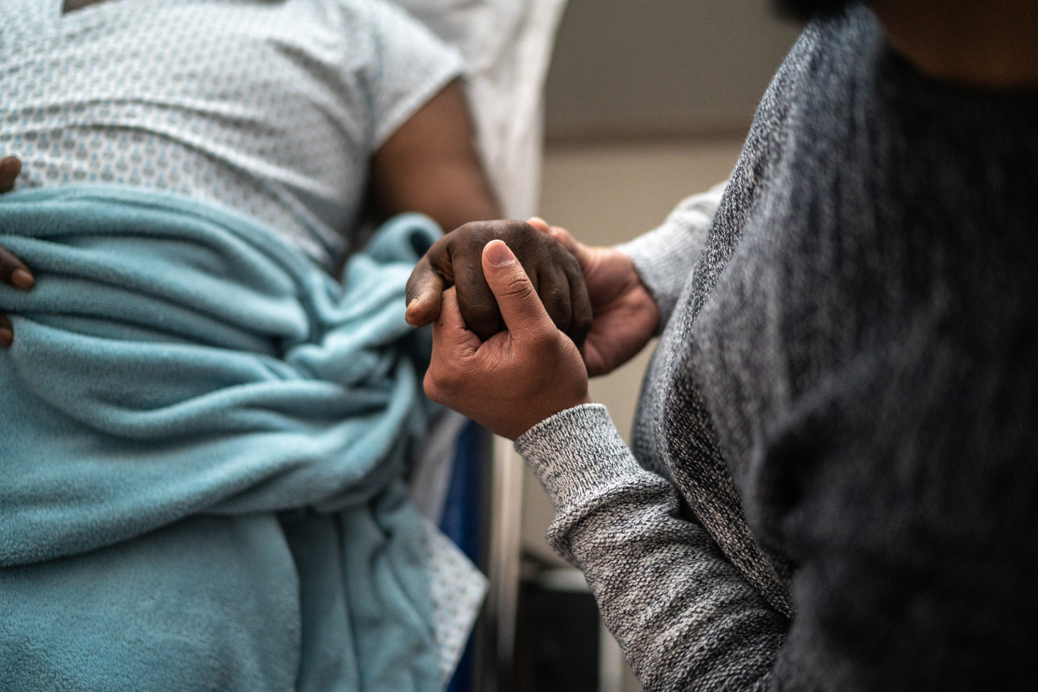 Son holding father's hand at the hospital Son holding father's hand at the hospital