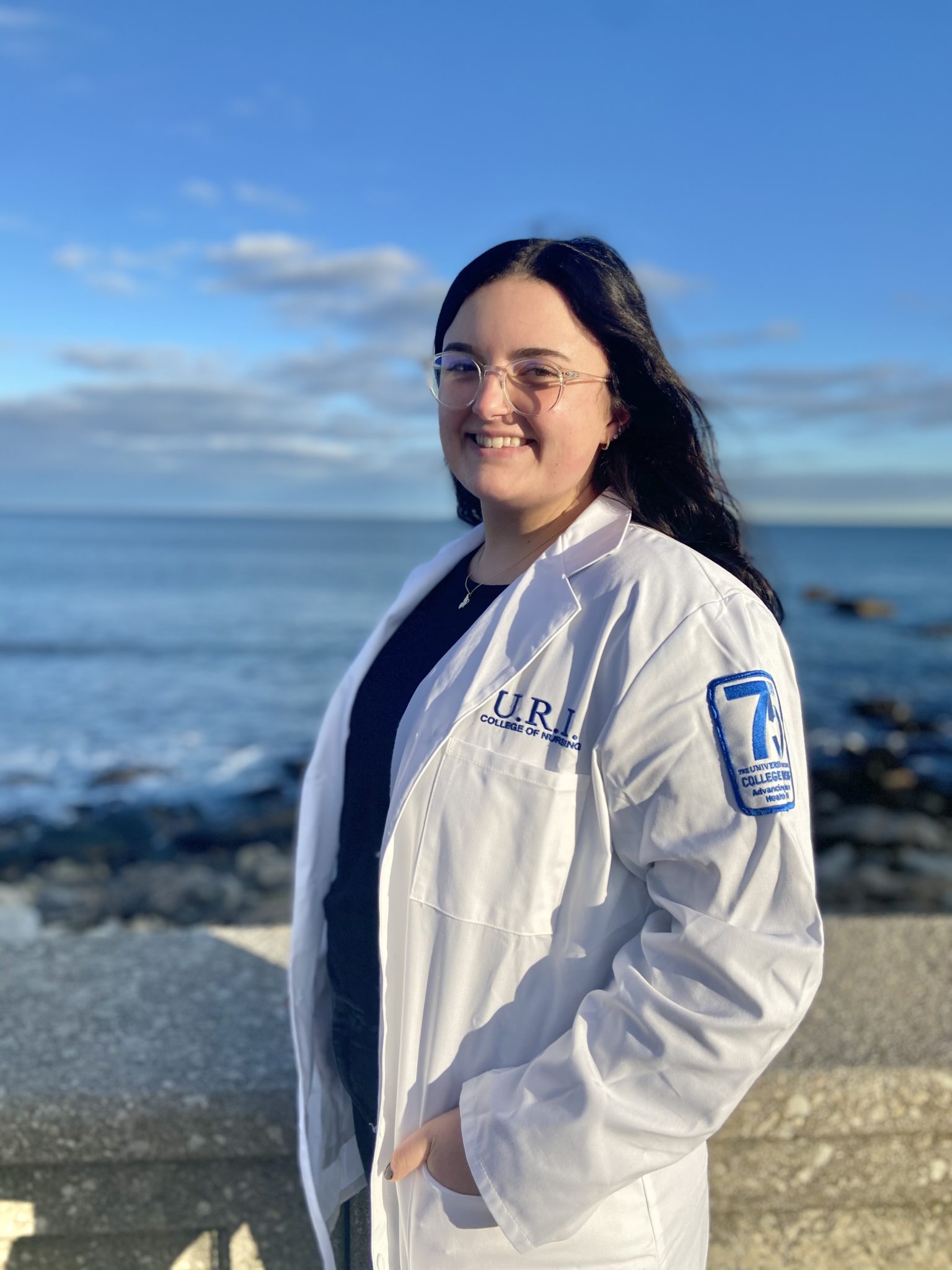student nurse in scrubs jacket standing in front of an ocean view