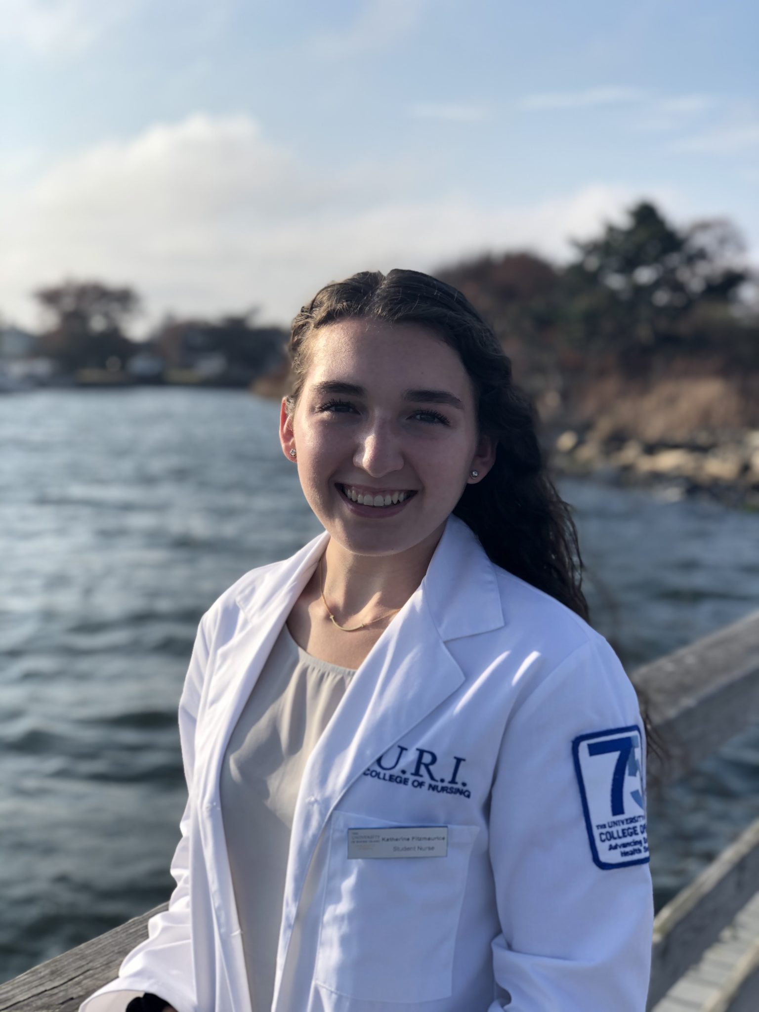 student nurse in scrubs jacket standing in front of an ocean view