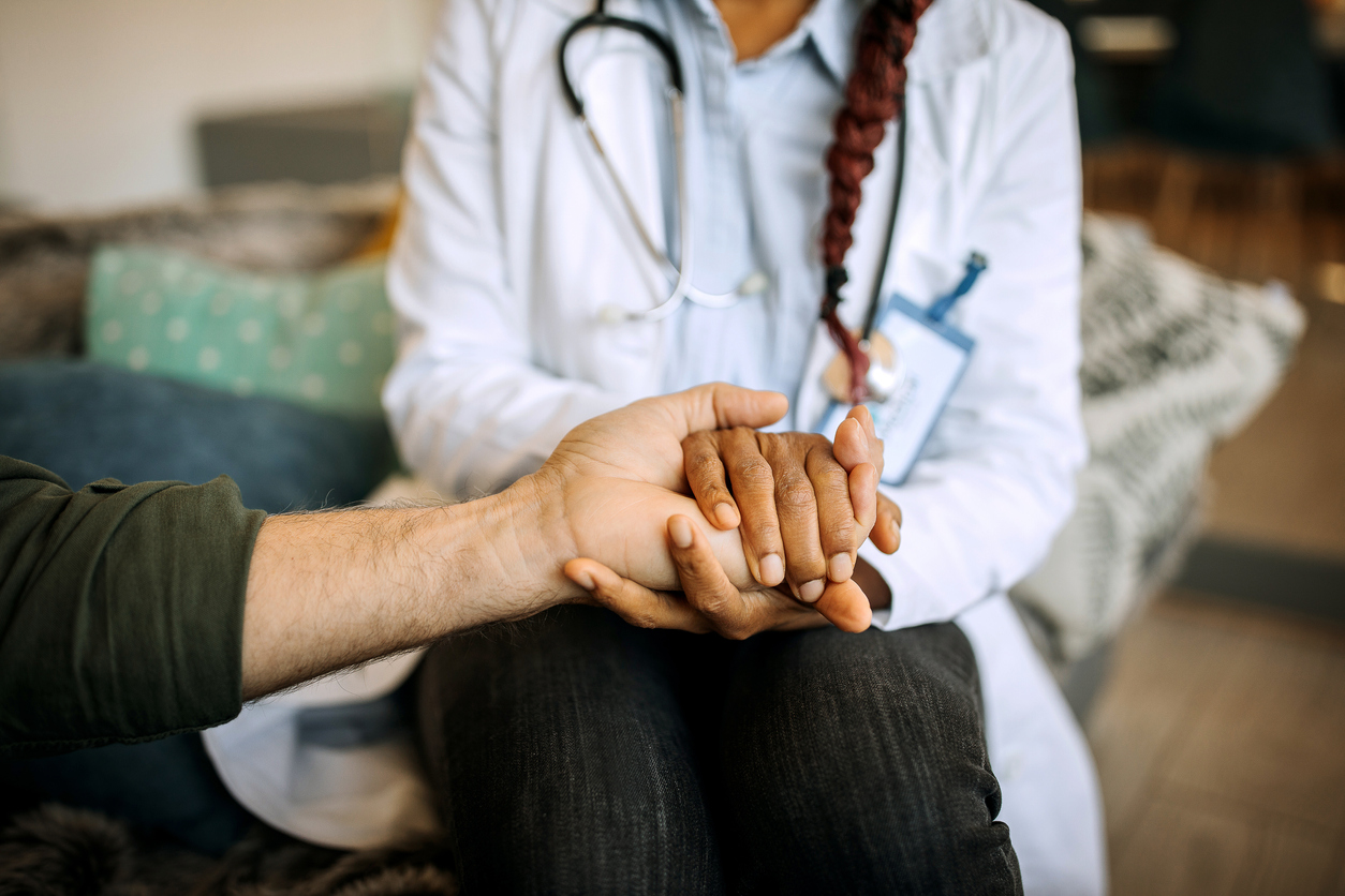 A female doctor consoles a senior patient at home