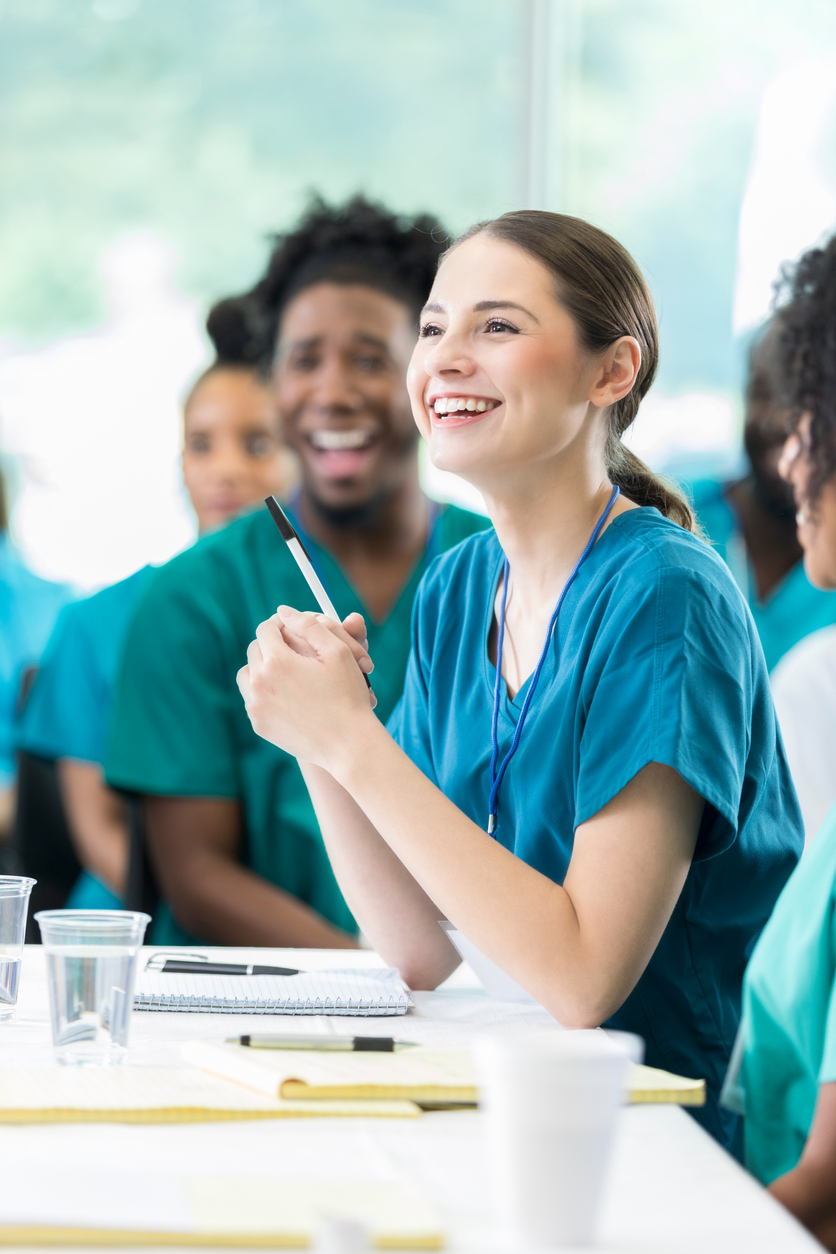 Cheerful female Hispanic female healthcare professional smiles while participating in panel discussion at healthcare conference or seminar.