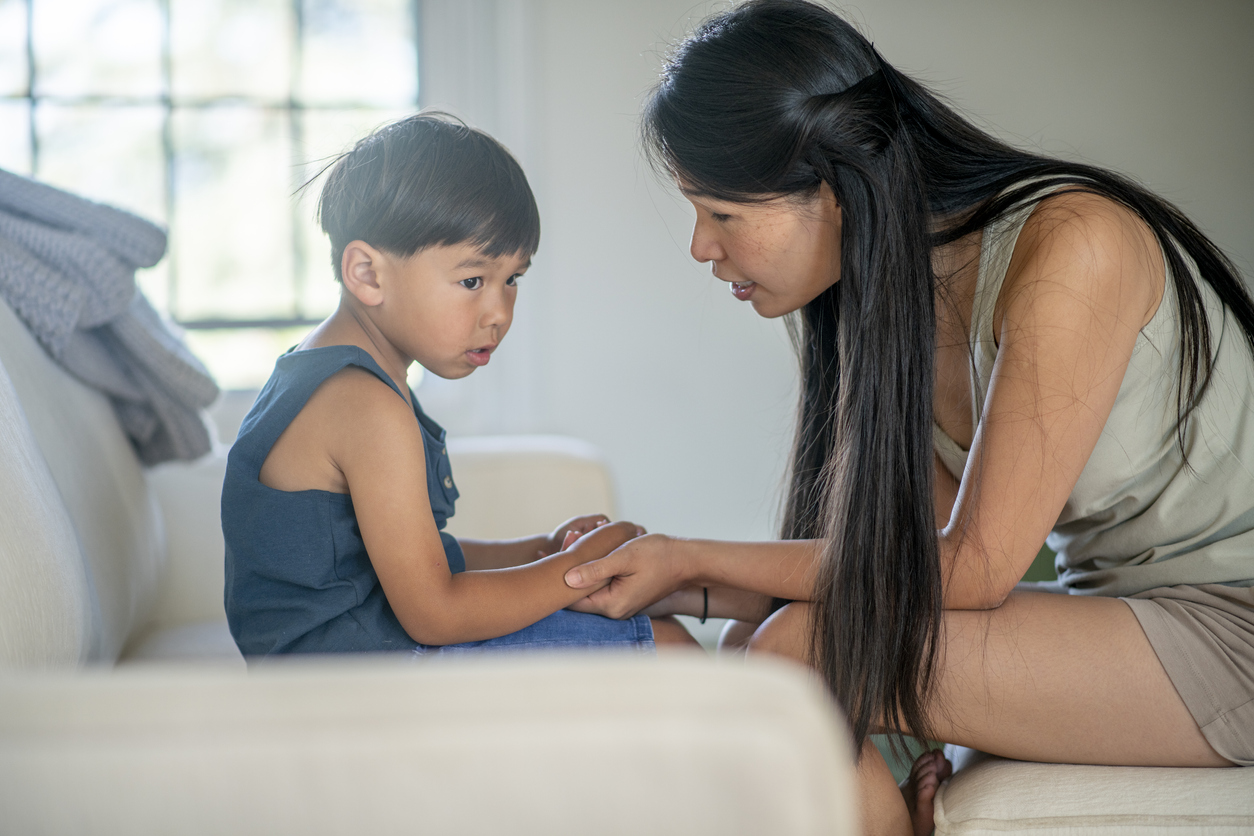 A boy contemplates while his mother holds his hands and explains life to him.