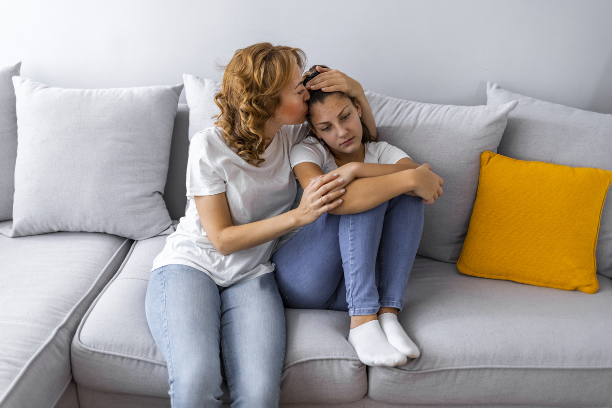 Mother Talking With Unhappy Teenage Daughter On Sofa