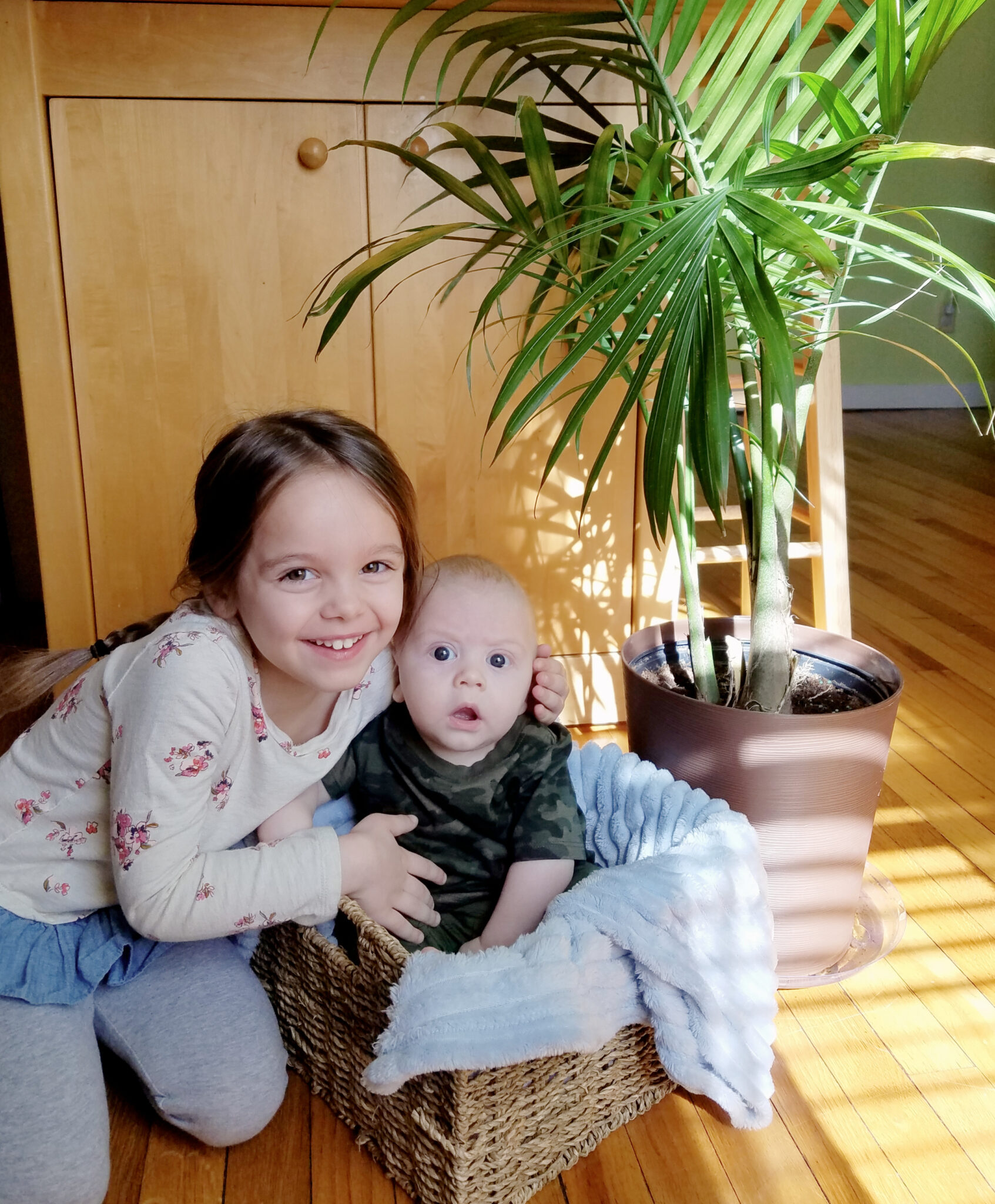 Sister cuddling with brother in a basket