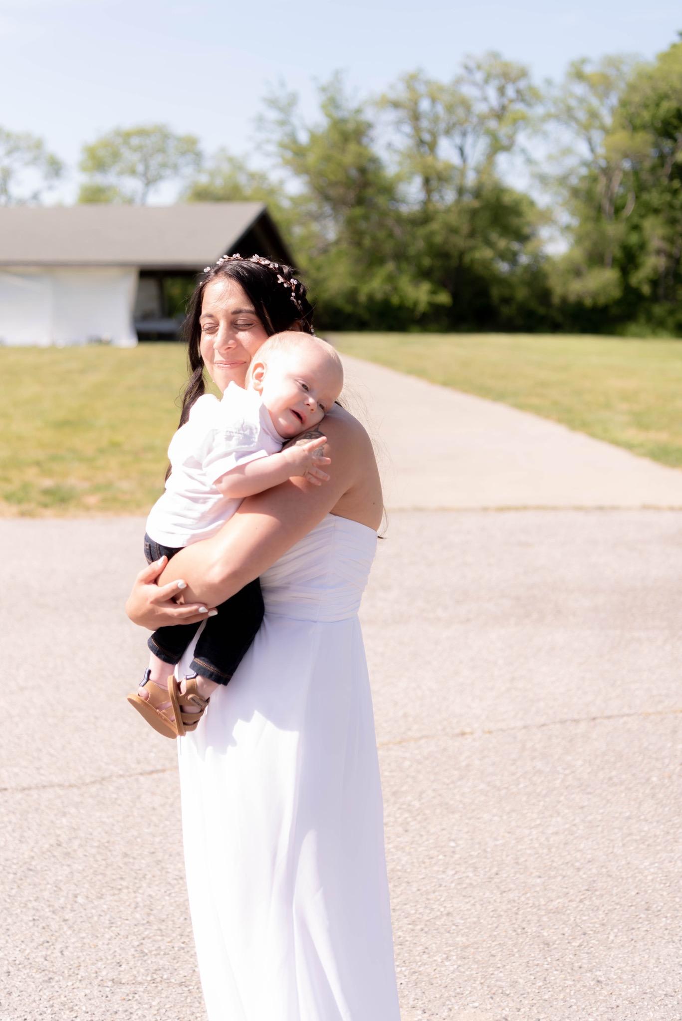 Mom in a white dress and a flower crown holding her baby boy in her arms
