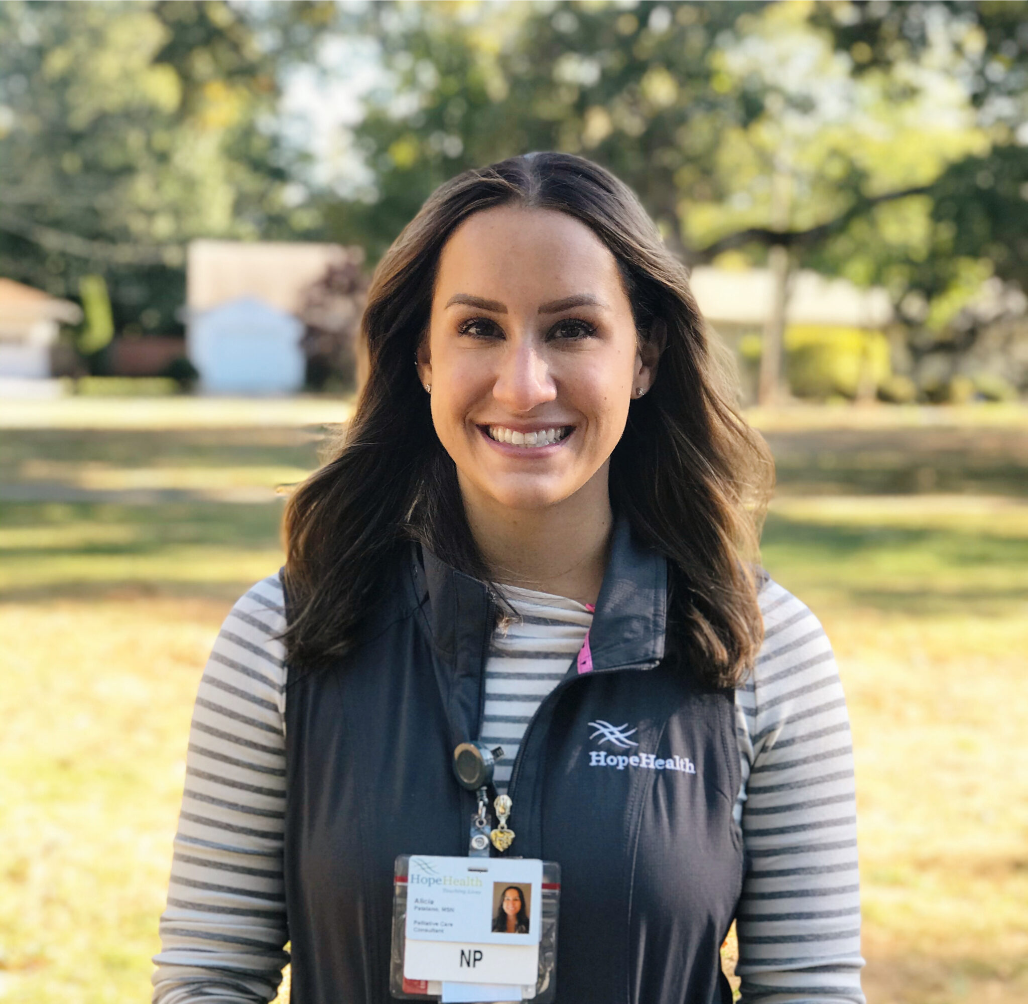 Palliative care nurse practitioner in a park wearing vest and badge