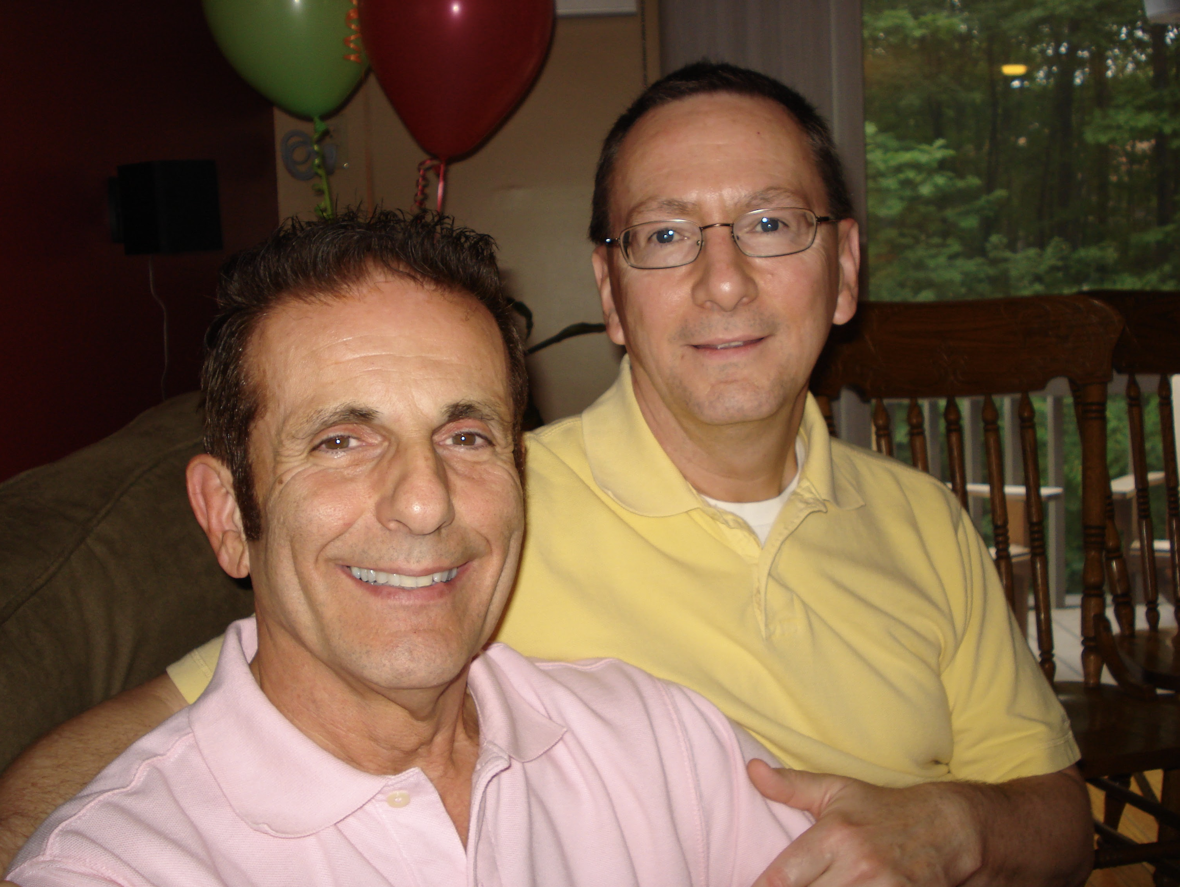 Two men embracing with balloons behind them