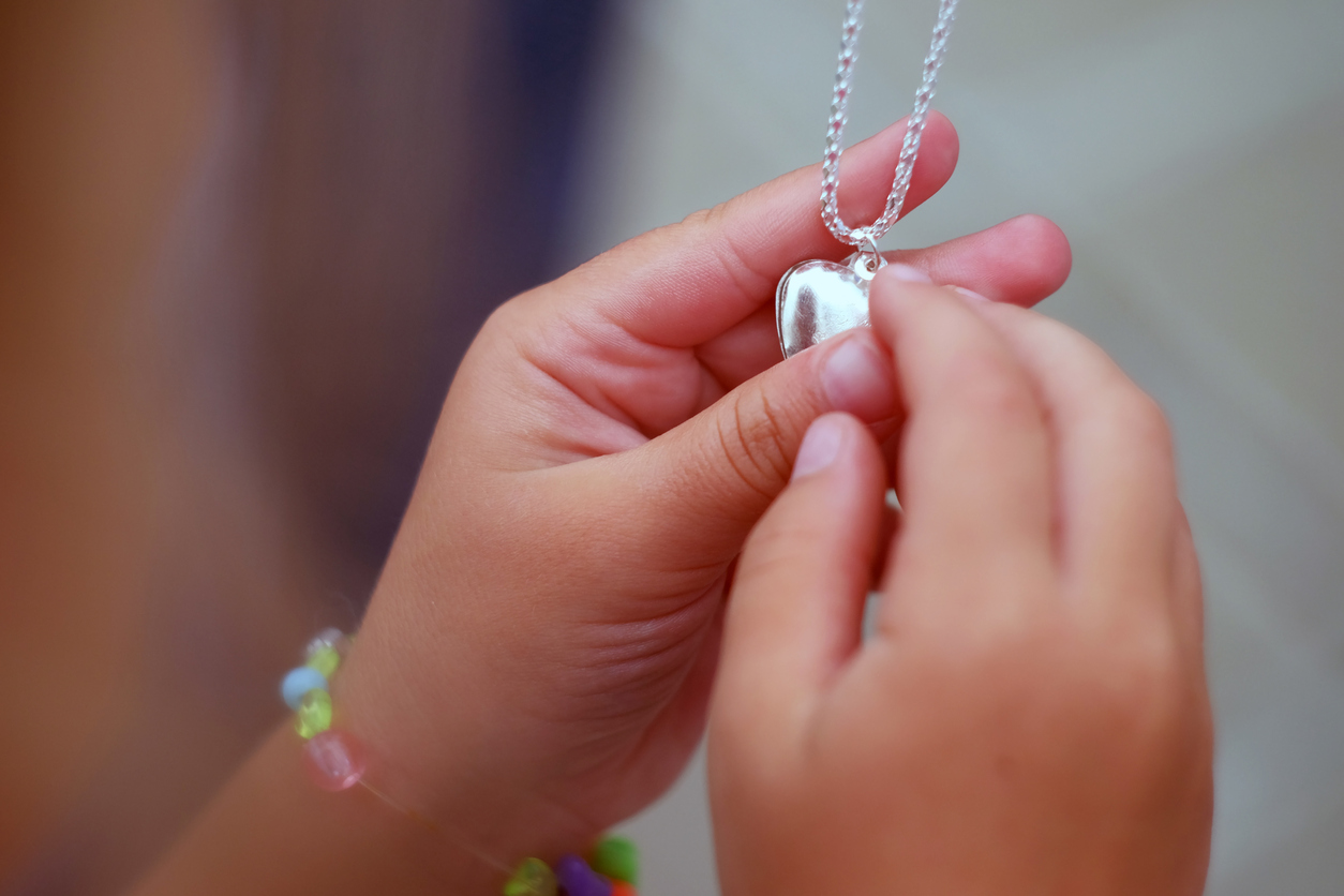 the pendant in the hands of children. Children's hands holding a beautiful chain with a pendant so close