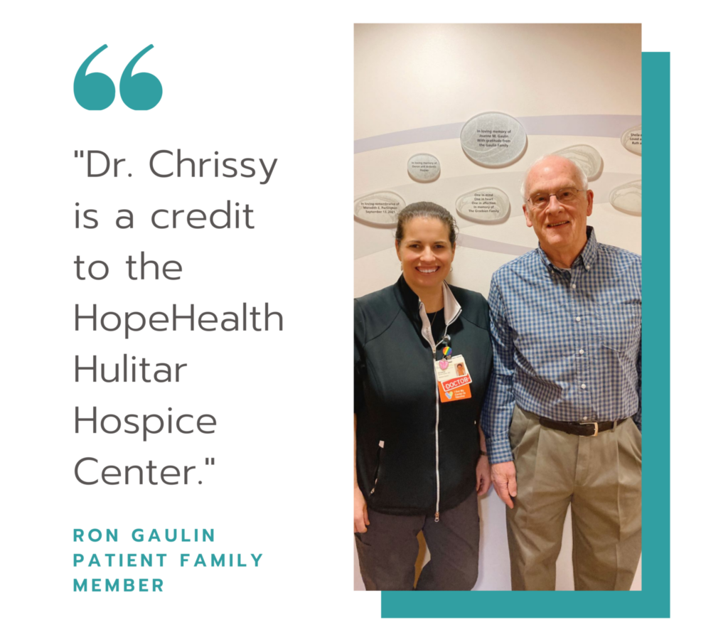 Large quote symbol with the words, "Dr. Chrissy is a credit to the HopeHealth Hulitar Hospice Center." Next to the quote is a photo of an elderly man standing with a woman in front of a remembrance wall at the Hulitar Hospice Center
