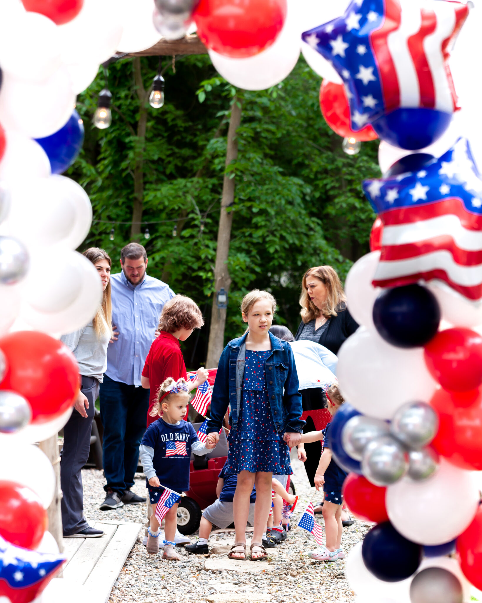 Children march under a patriotic arch of balloons