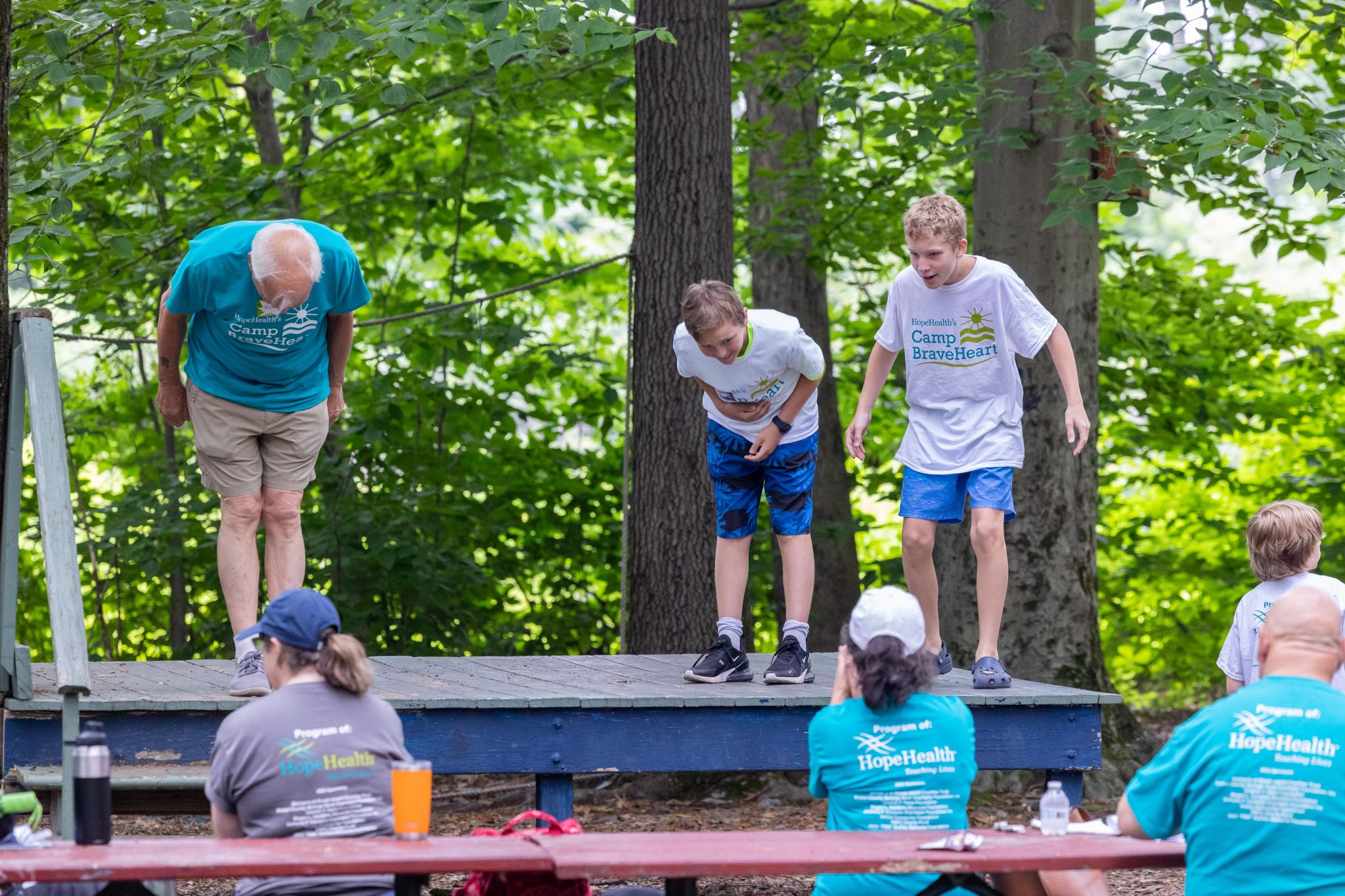 Older man and two boys bow on a theater stage after a performace at Camp BraveHeart, HopeHealth's grief support camp