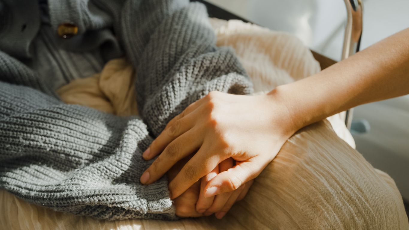 Closeup of young Asian people holding hands trust comfort help cancer patients talk crying stress relief in living room at home. Healthcare concept.