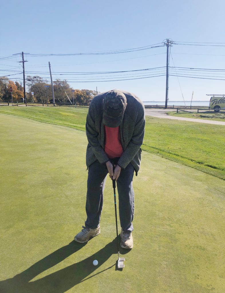 Man in baseball cap looking down getting ready to putt