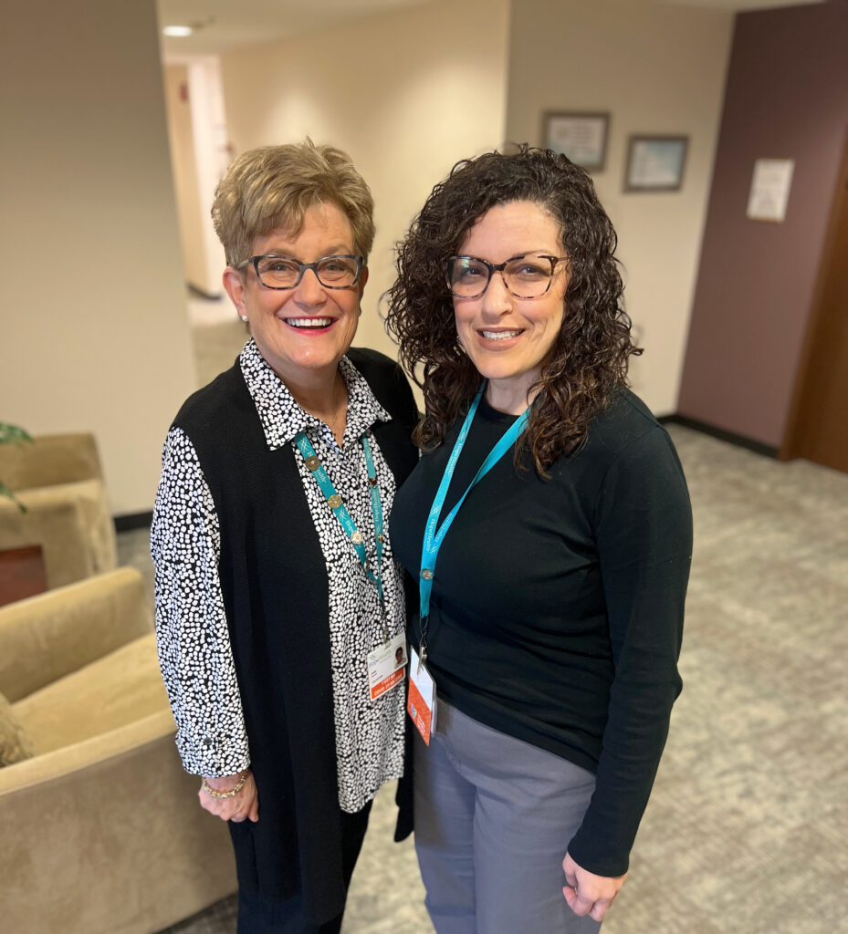 Two women standing next to each other with big smiles.