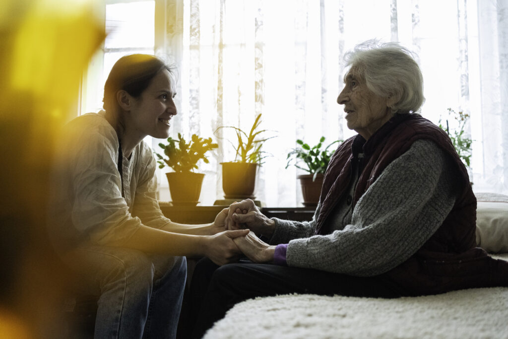 Volunteer woman caretaker talking with senior woman.