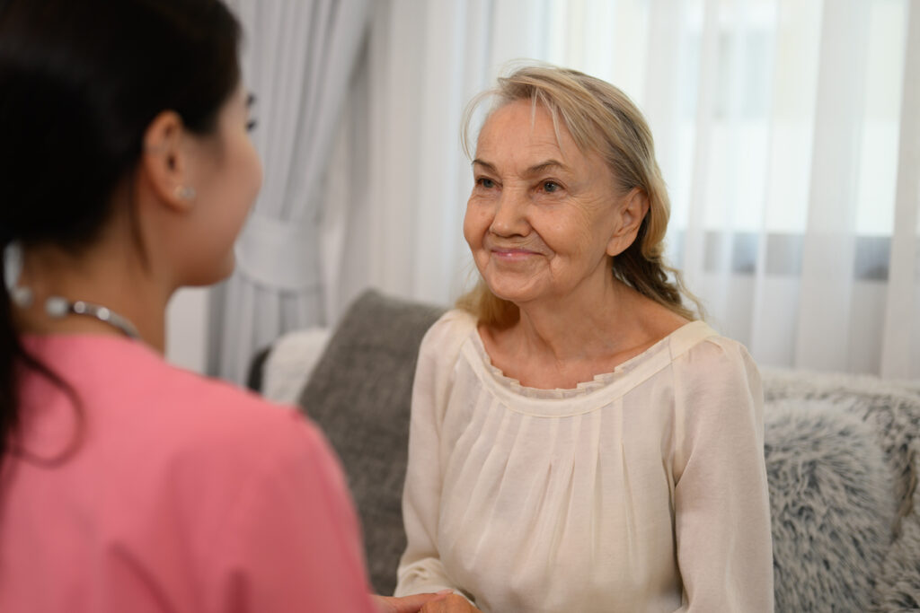 Happy doctor or nurse caregiver with senior patient at home or nursing home, Professional female doctor with stethoscope visiting patient, Doctor and senior woman during home visit