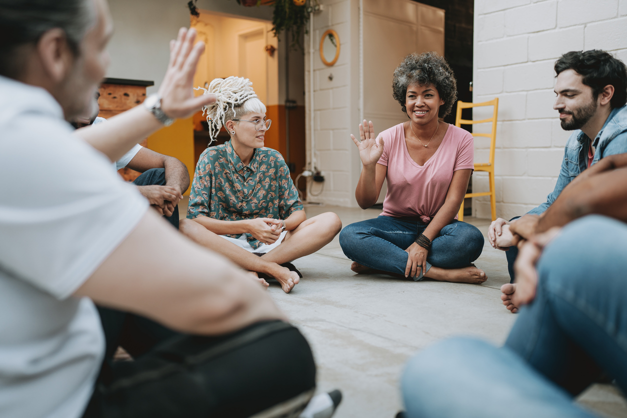 Group of people sitting cross legged in a circle for a LGBTQ+ caregiver support group
