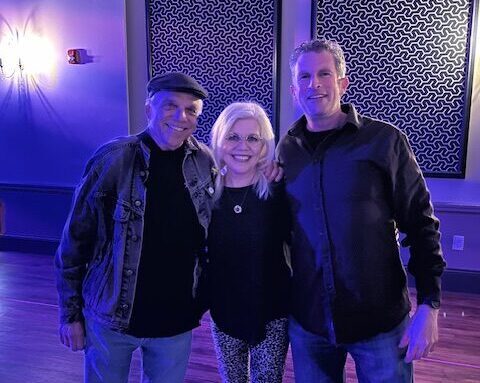 A blond woman standing between two men