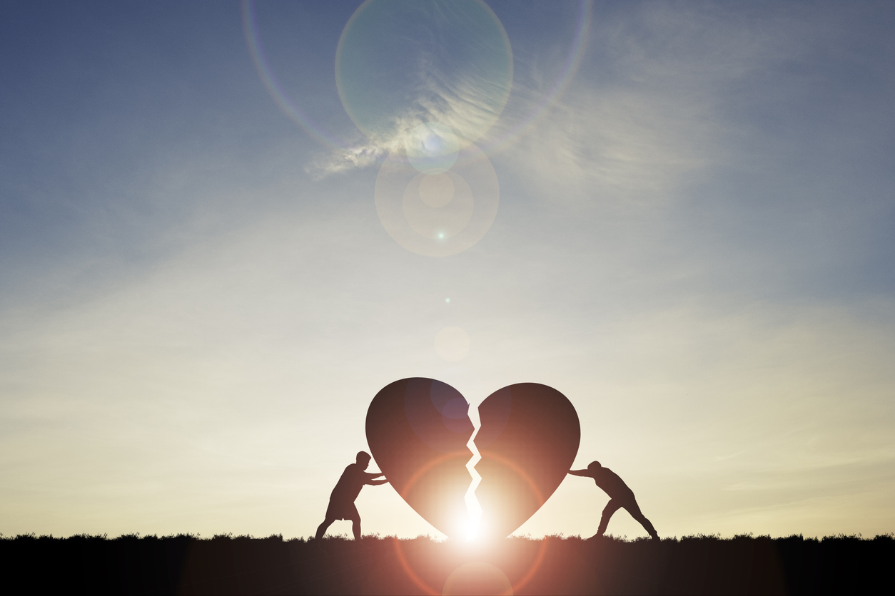 Two silhouette men pushing broken heart with sunlight and blue sky , Valentine 's day concept.