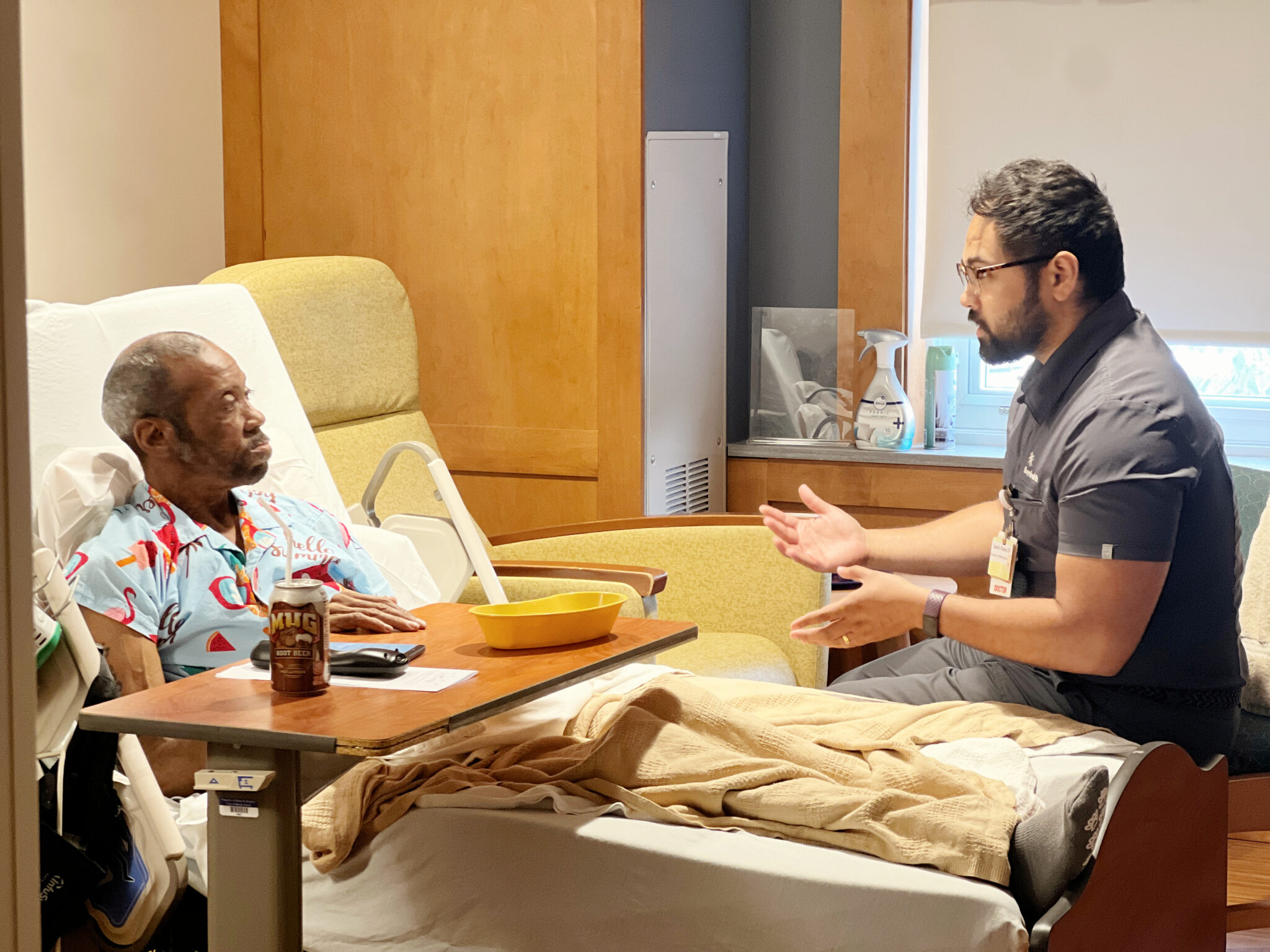 A patient sits in his hospice bed, talking to his doctor