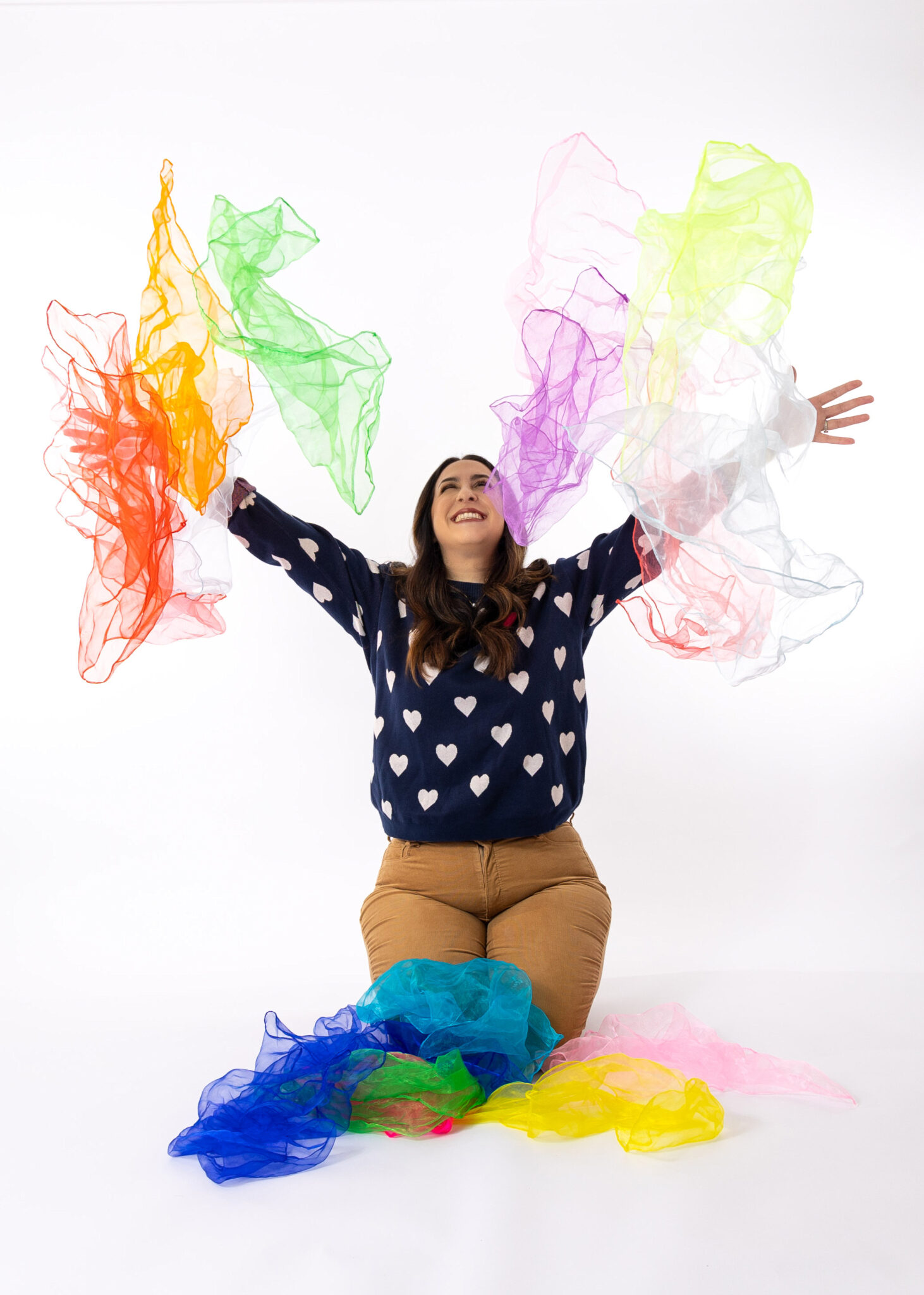 Dance/Movement Therapist for PediPal Services throws colorful fabric in the air, against a white background