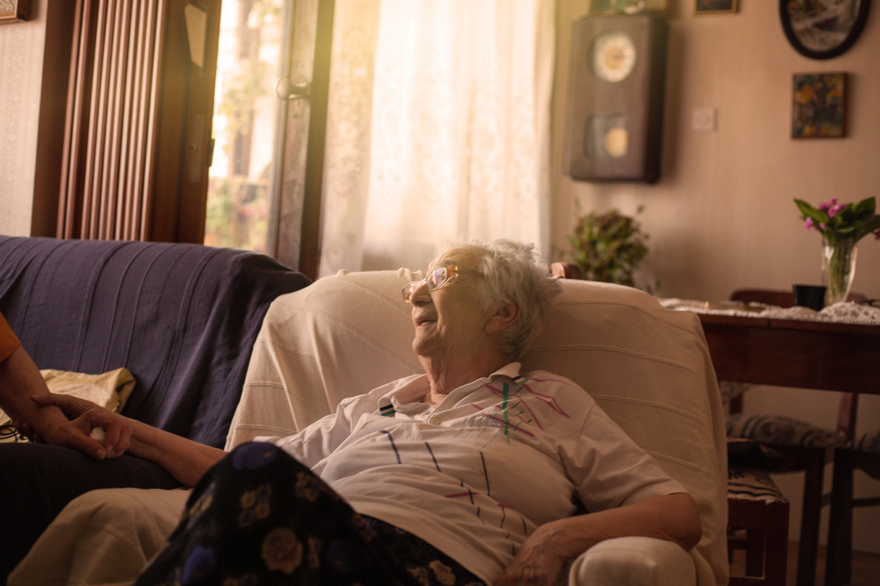 Portrait of smiling old woman sitting on sofa.