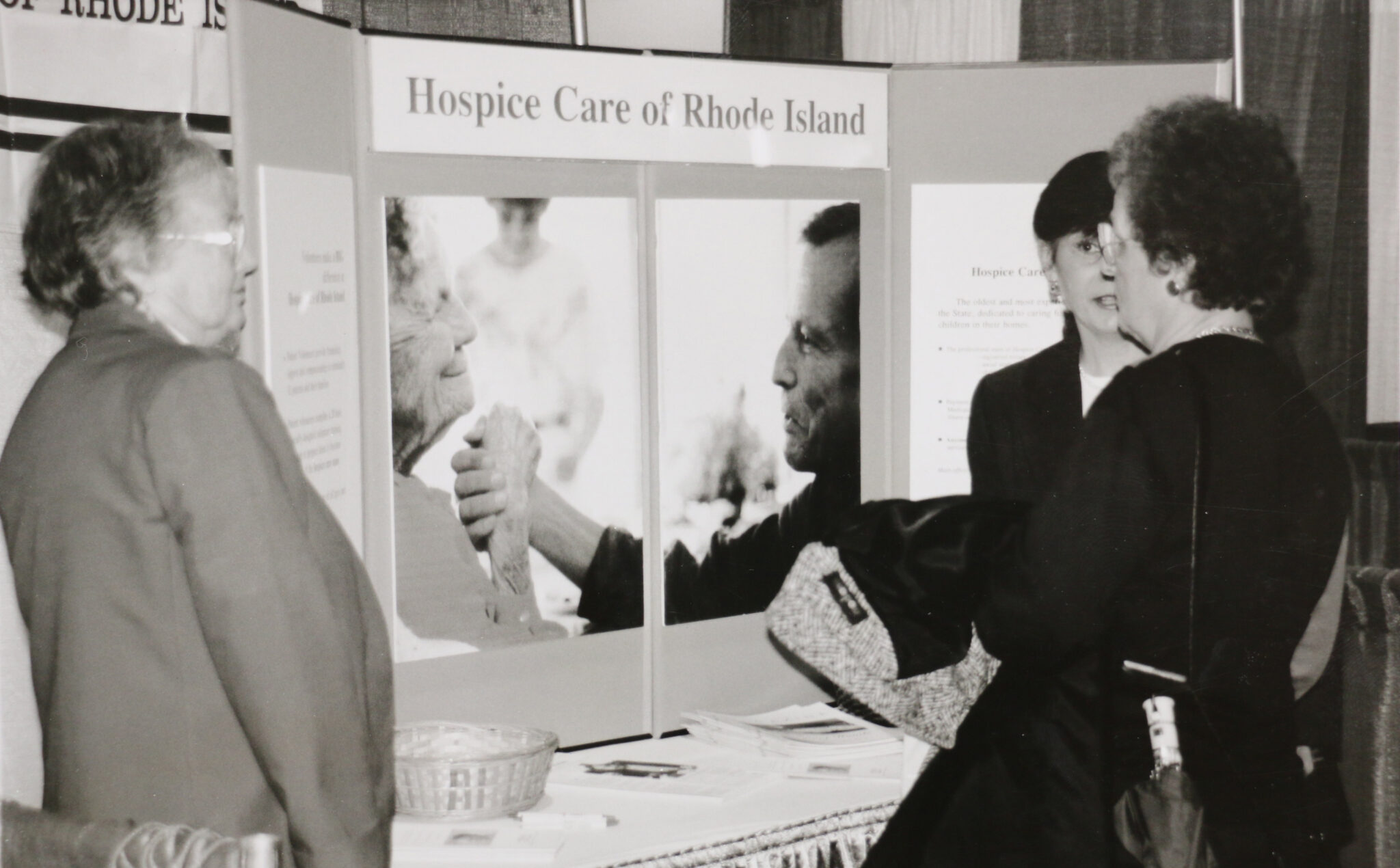 Historical black and white photo of someone presenting a poster board about hospice care