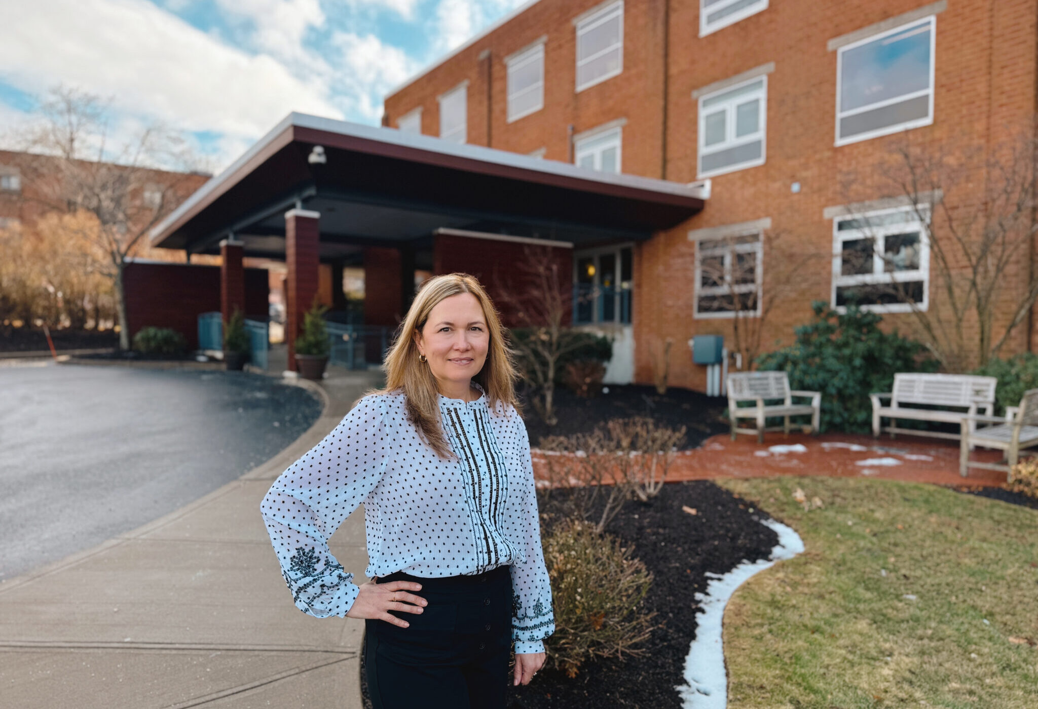 Female pharmicist standing in front of brick Hulitar Hospice Center in Providence, RI