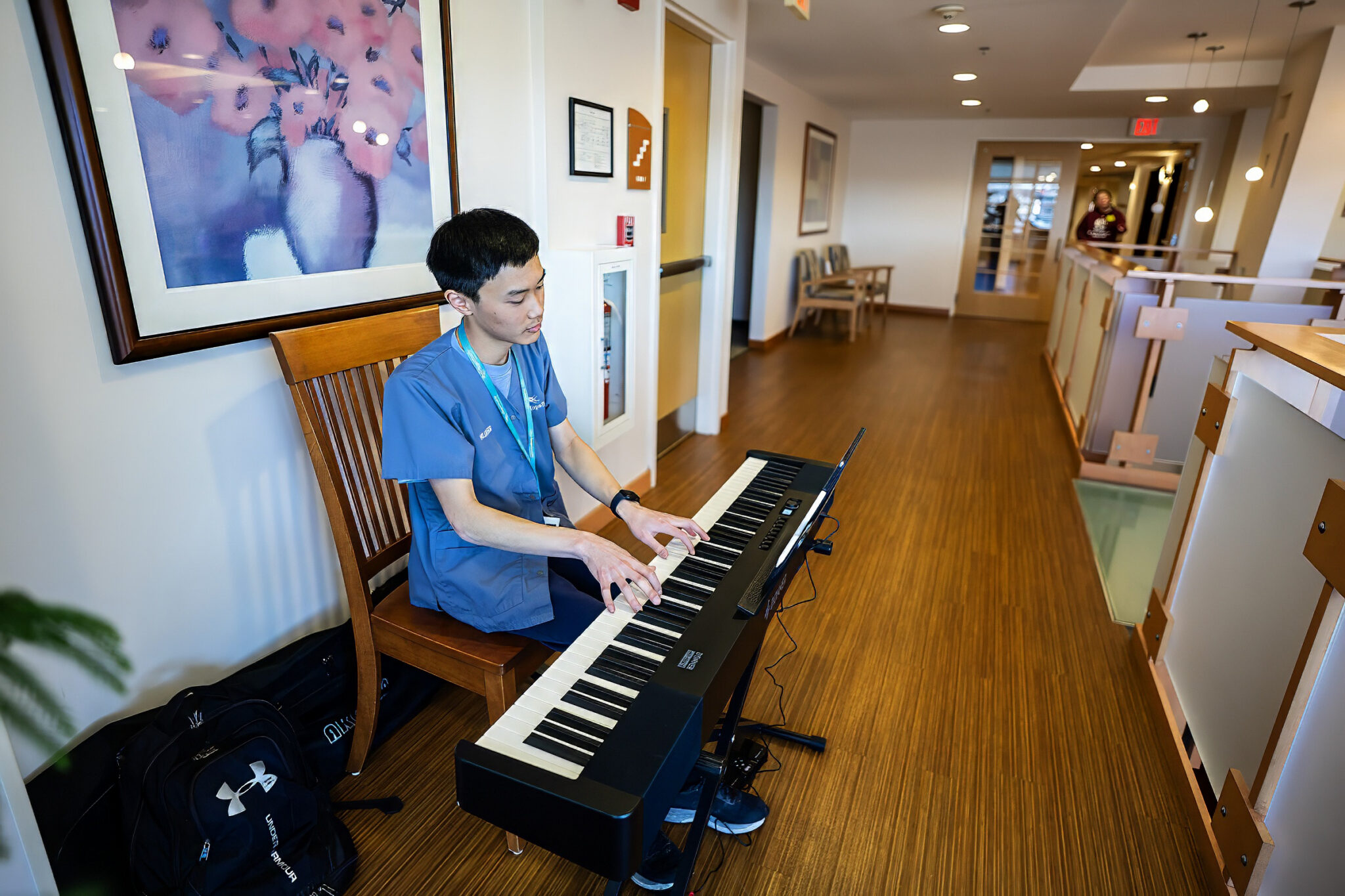 young musician volunteer sits at keyboard at the Hulitar Hospice Center playing music for patients and families
