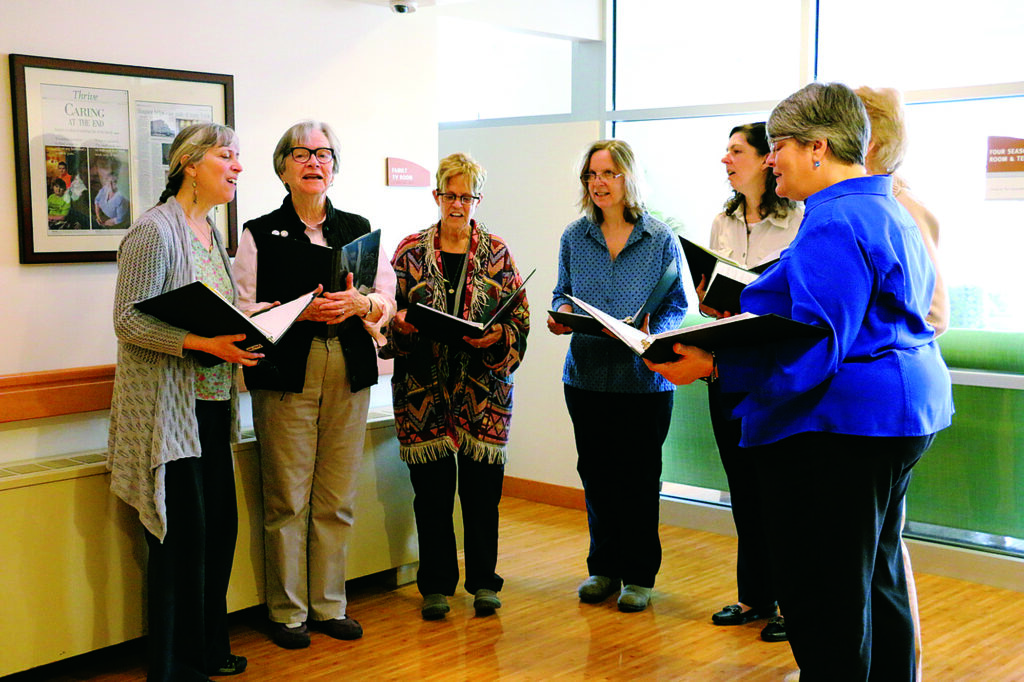 Group of women from Grace Notes Singers gather around to sing at the HopeHealth Hulitar Hospice Center