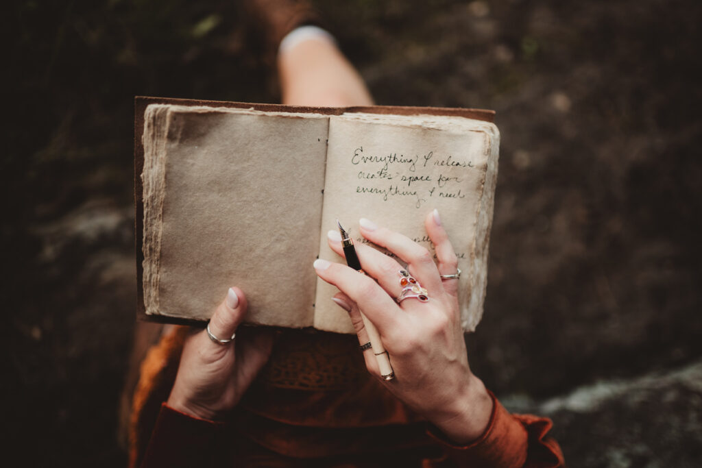 Woman sitting outdoors writing in her journal to cope with grief