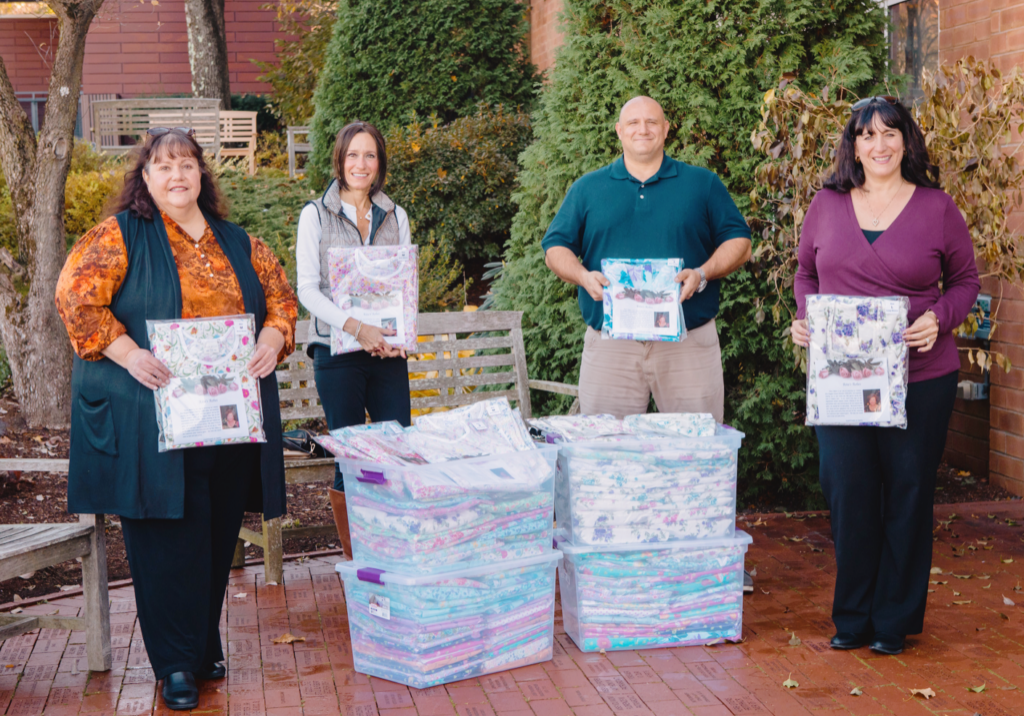 Brothers and sisters hold up Rita's robes, a donation of specially-made patient gowns for hospice patients