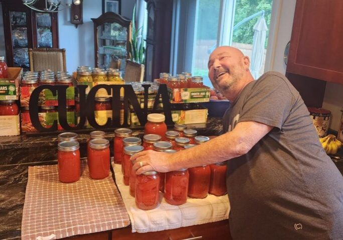 Man standing with his many jars of tomato sauce
