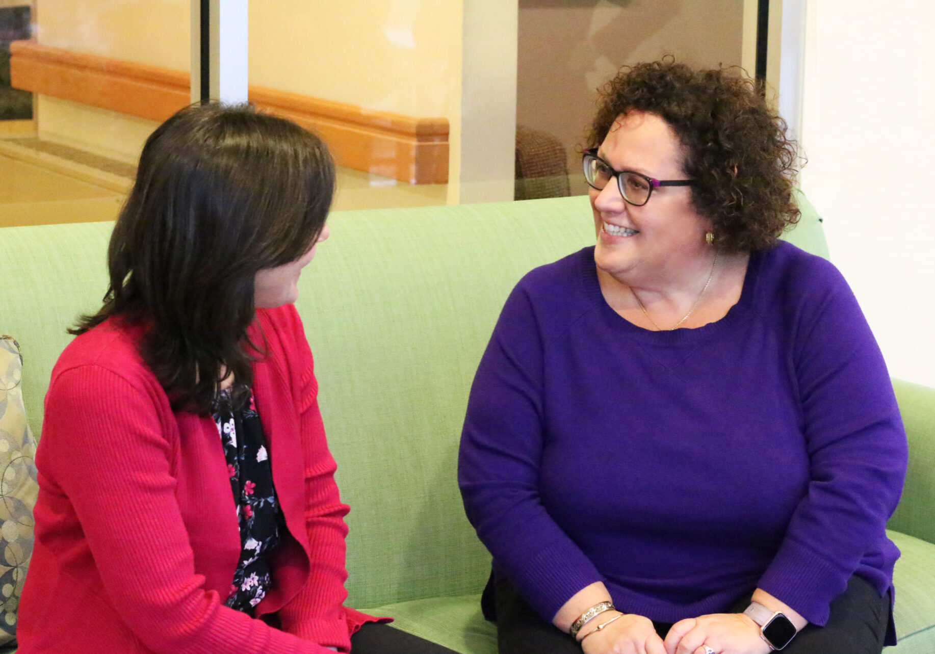 Two women smiling on a couch together