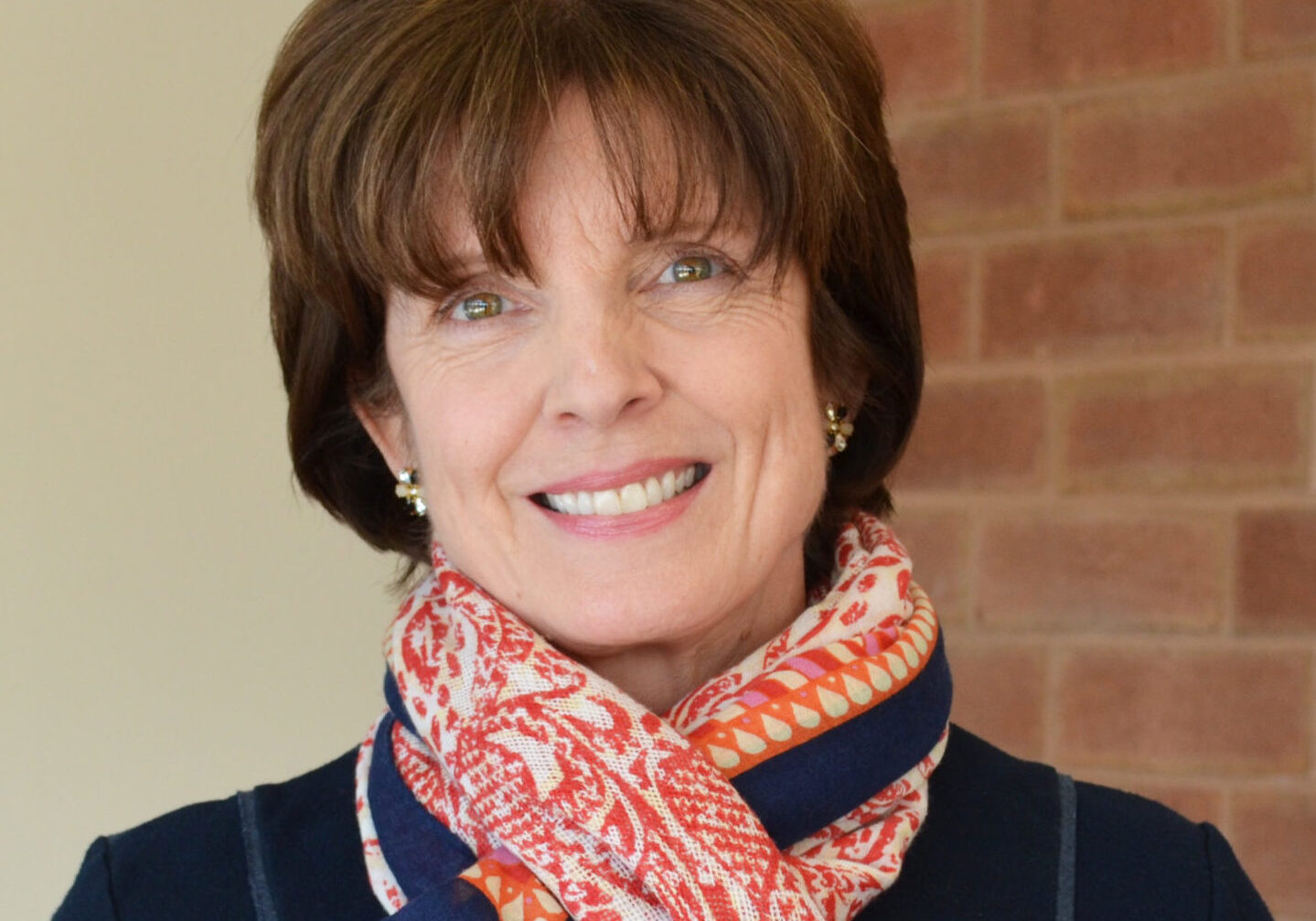 Woman smiling with a bright navy blue and red scarf around her neck