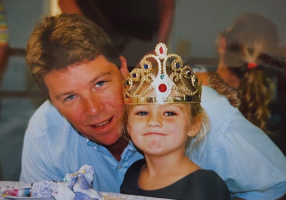 C8529472-5B86-48EF-8048-741A457D864B Young girl wearing a golden crown next to her dad