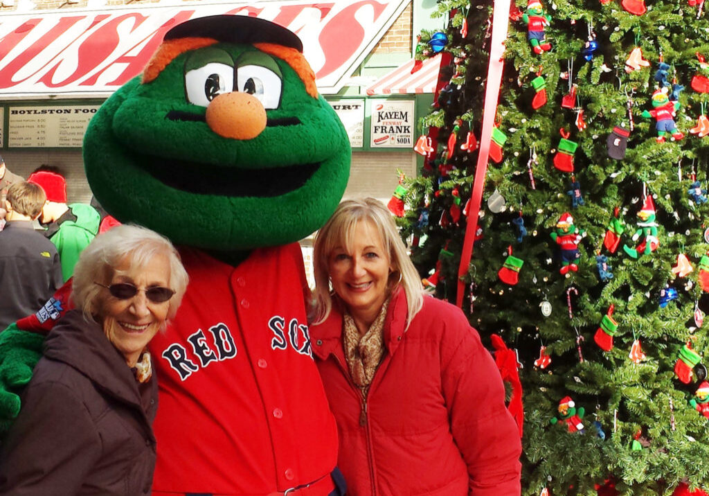 Mom and elderly mom with the Red Sox mascot next to a Christmas tree