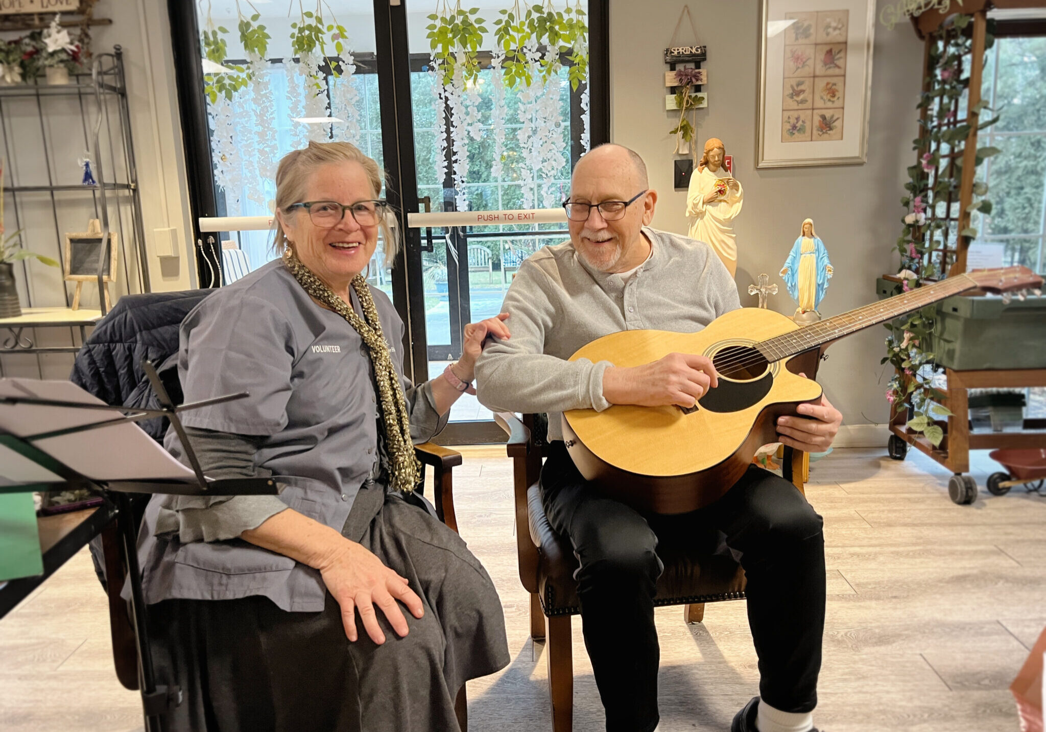 Crystal Volunteer and Richard Man and woman sitting. The man is holding a guitar.