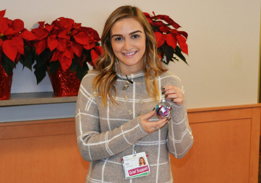 Young woman smiling with holiday remembrance ornament in her hand