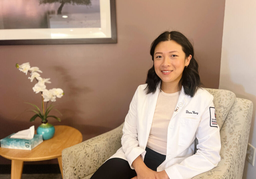 Brown University medical student sitting in chair next to a table with a plant and tissues