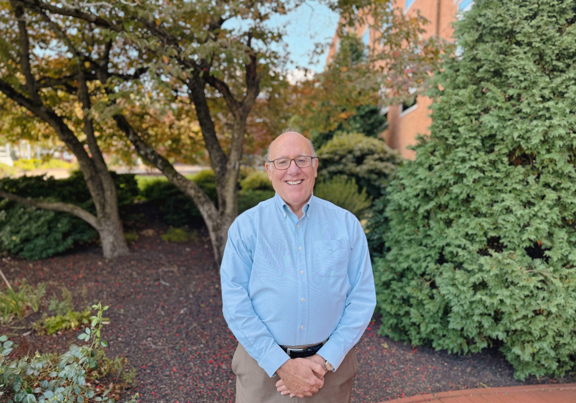 Man in blue button down standing amongst greenery