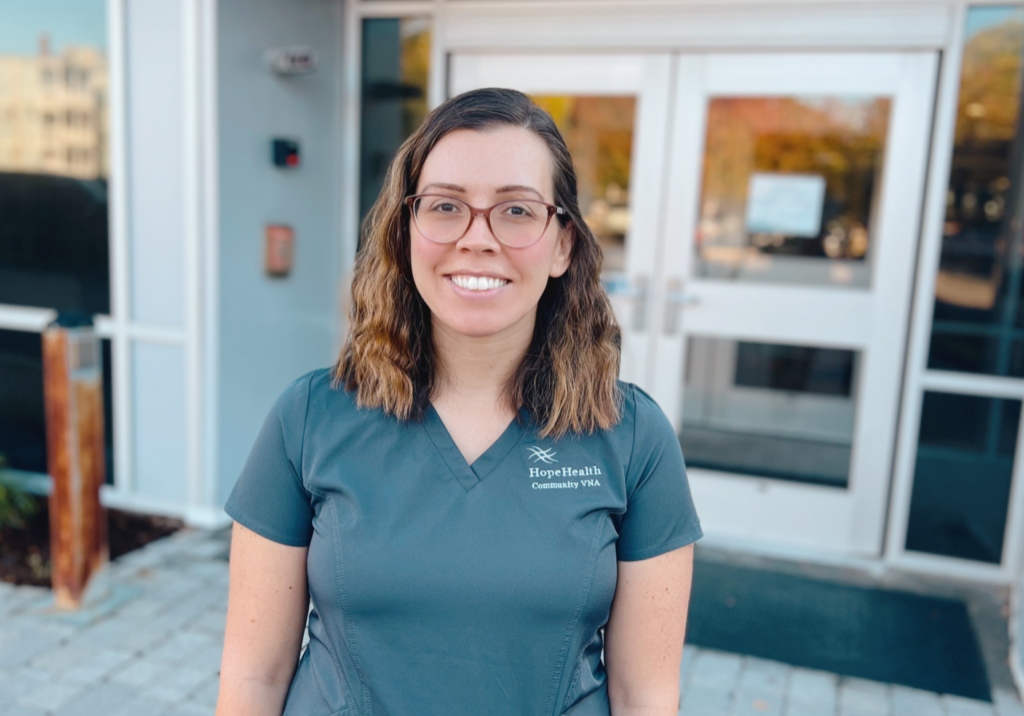 Physical therapist in gray scrubs stands in front of a building