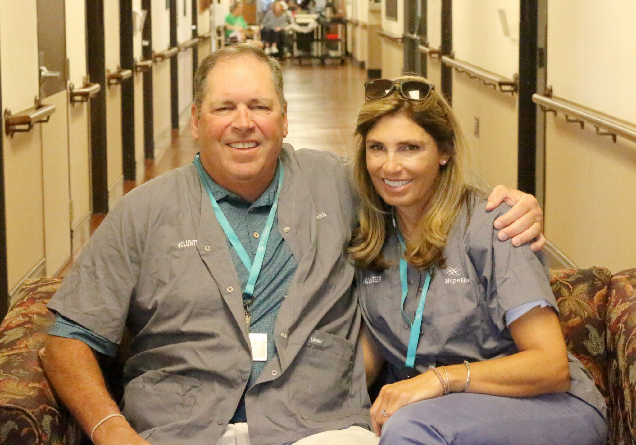 Husband and wife sit on a couch at a nursing home in Attleboro, Massachusetts where they are hospice volunteers