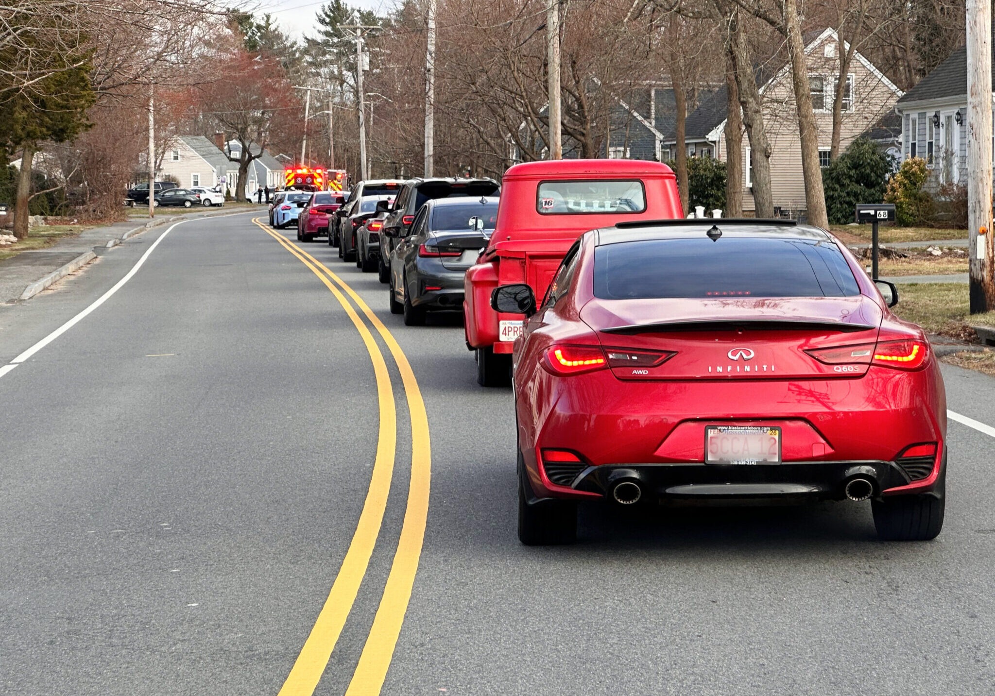 A row of cars lines up along the road to surprise a pediatric hospice patient