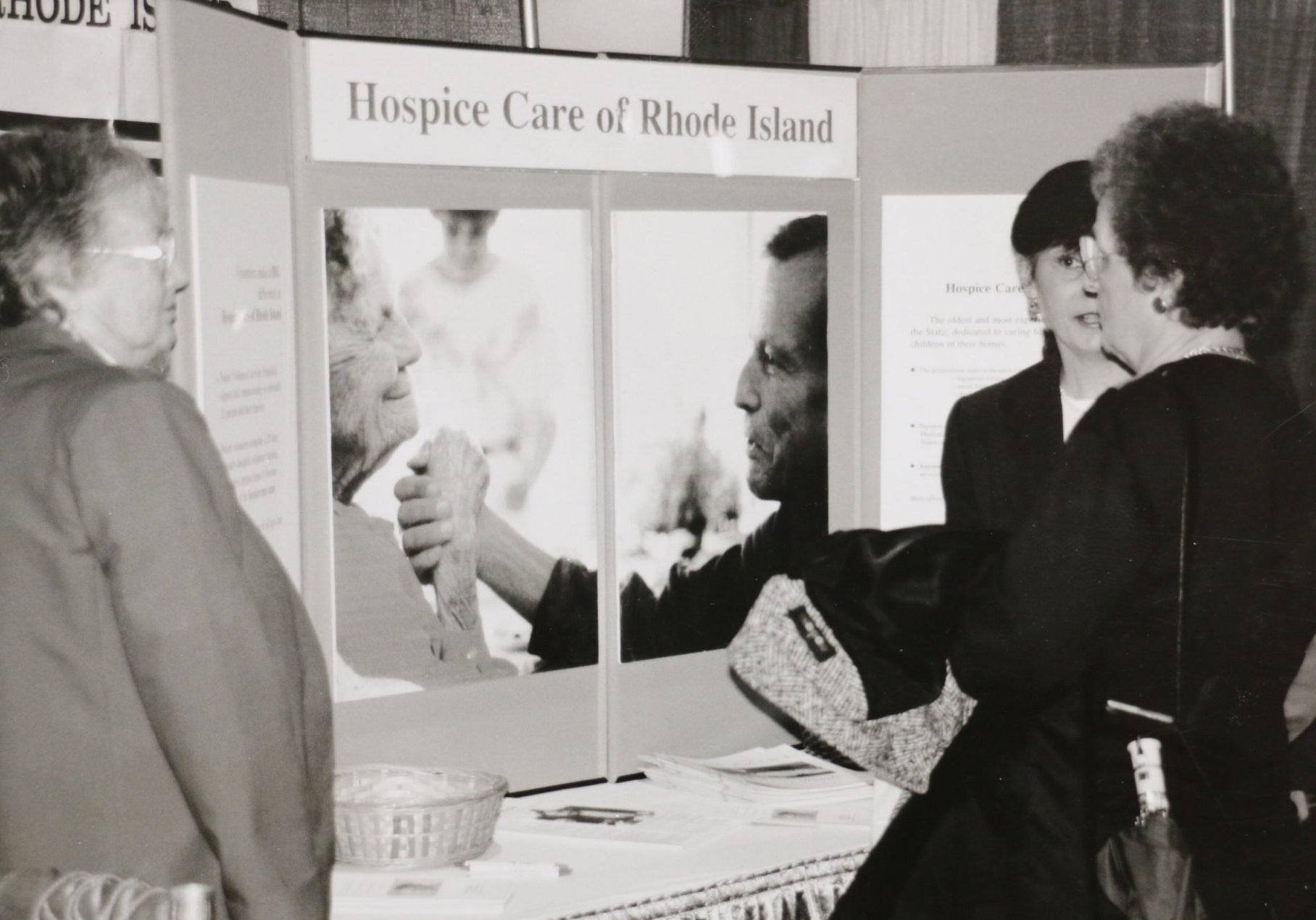 Historical black and white photo of someone presenting a poster board about hospice care